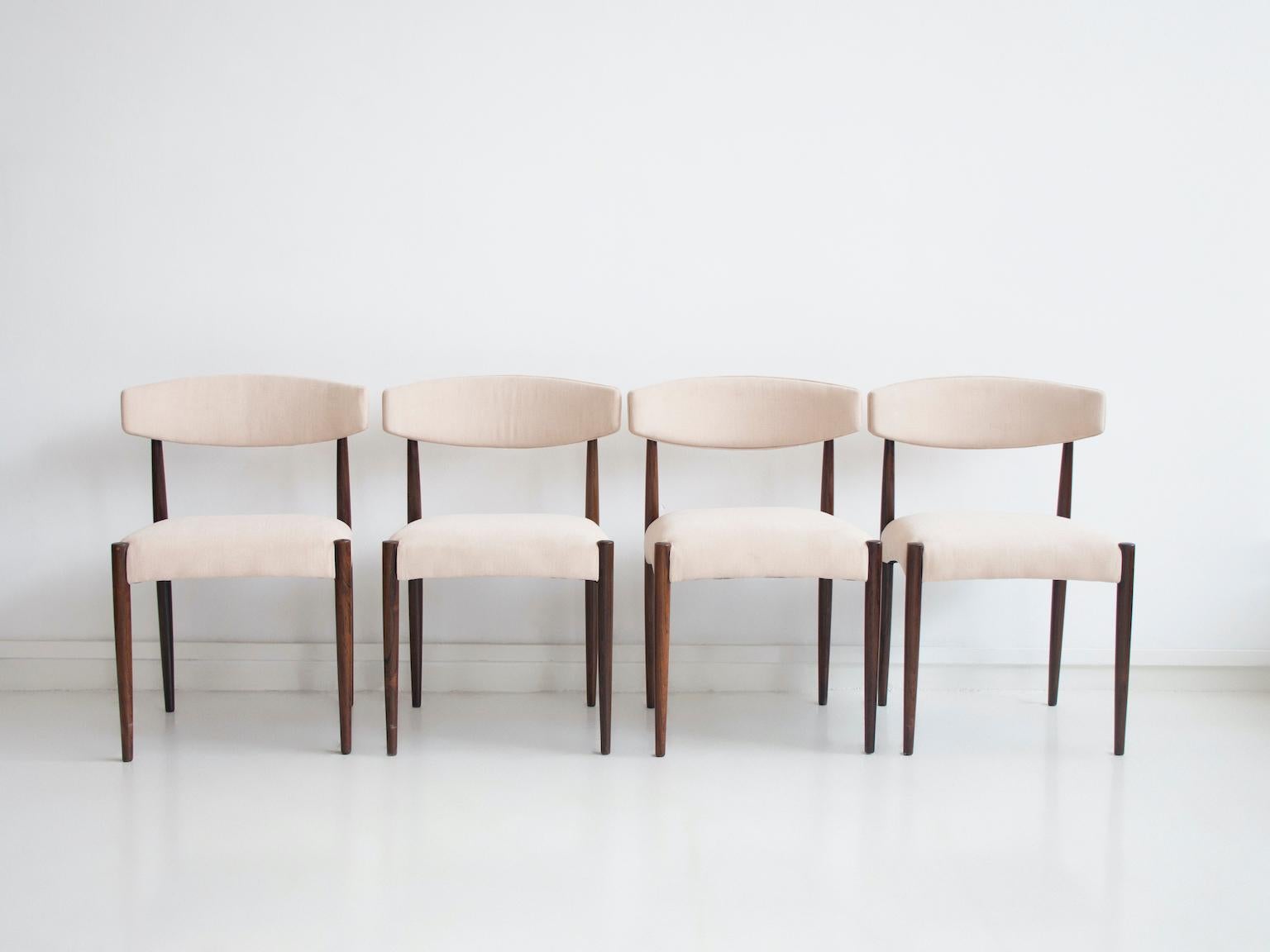 Satz von vier Esszimmerstühlen, hergestellt in Dänemark um 1960. Der Rahmen mit den schlanken Beinen ist aus Königsholz gefertigt. Sitz und Rückenlehne mit späterer Polsterung in hellem Stoff.