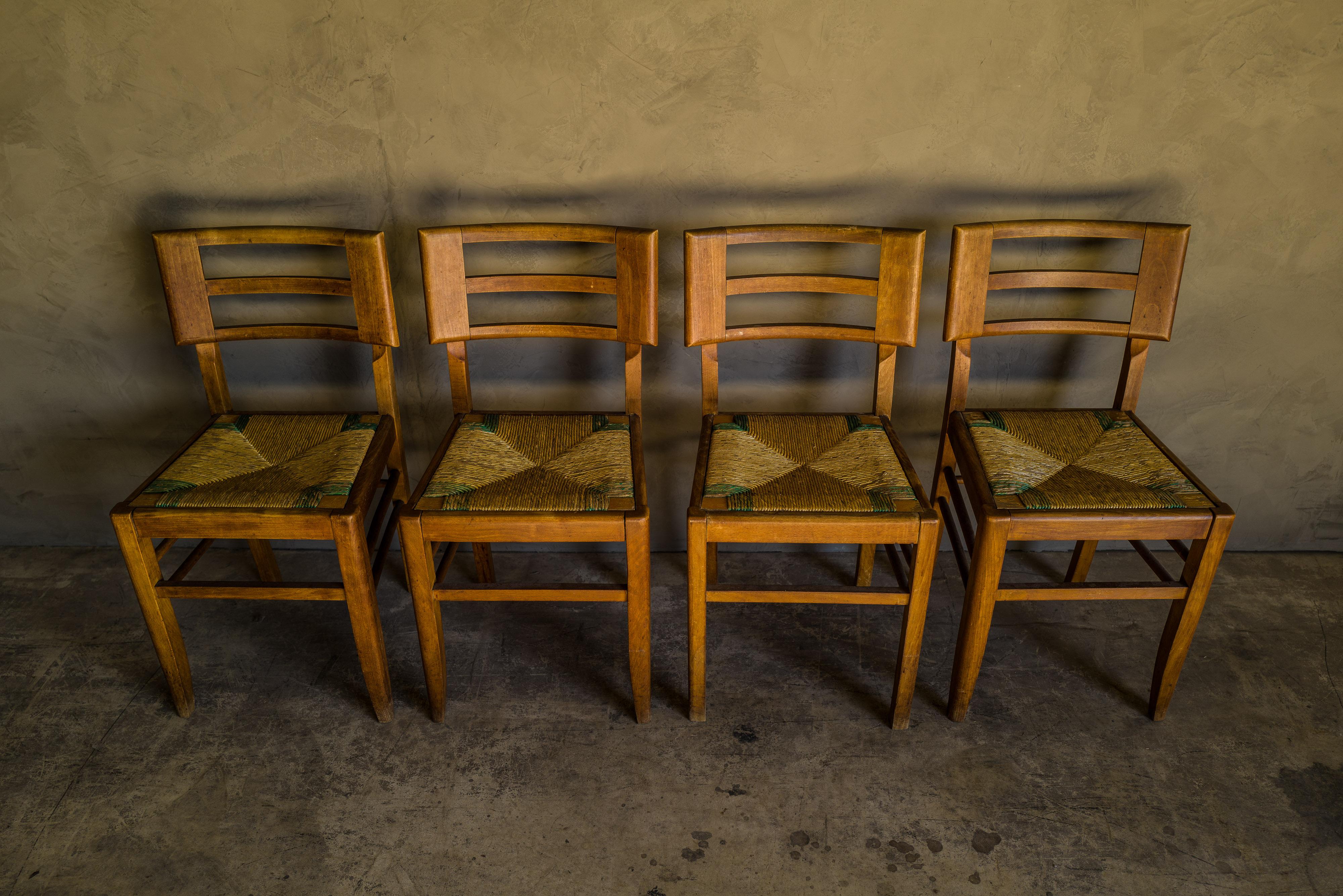Set of four dining chairs by Pierre Cruege, France, 1940s. Solid oak construction with cane seats. Light wear and patina.