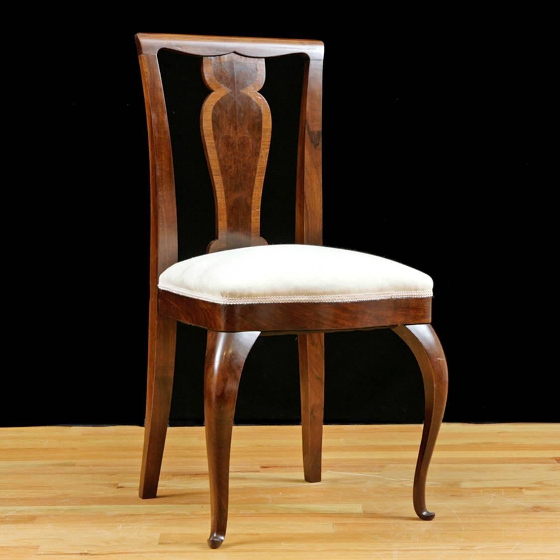 A handsome set of four dining chairs in rosewood with carved splat banded in a lighter wood, cabriole front legs and upholstered seat, Northern Europe, circa 1910. Chairs have been French-polished and upholstered in a cream-colored