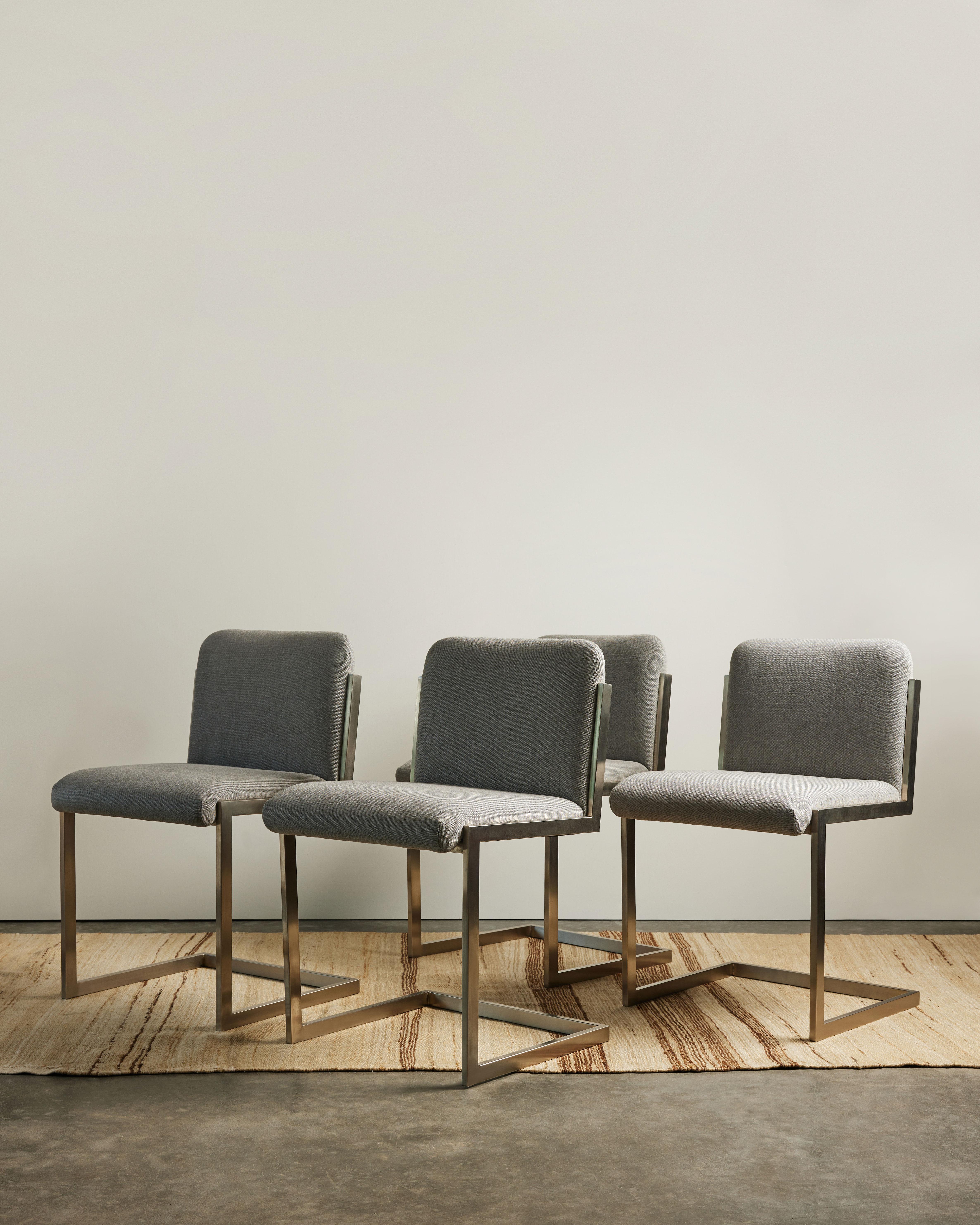 Set of four sleek, simple dining chairs with cantilevered seats; newly upholstered.