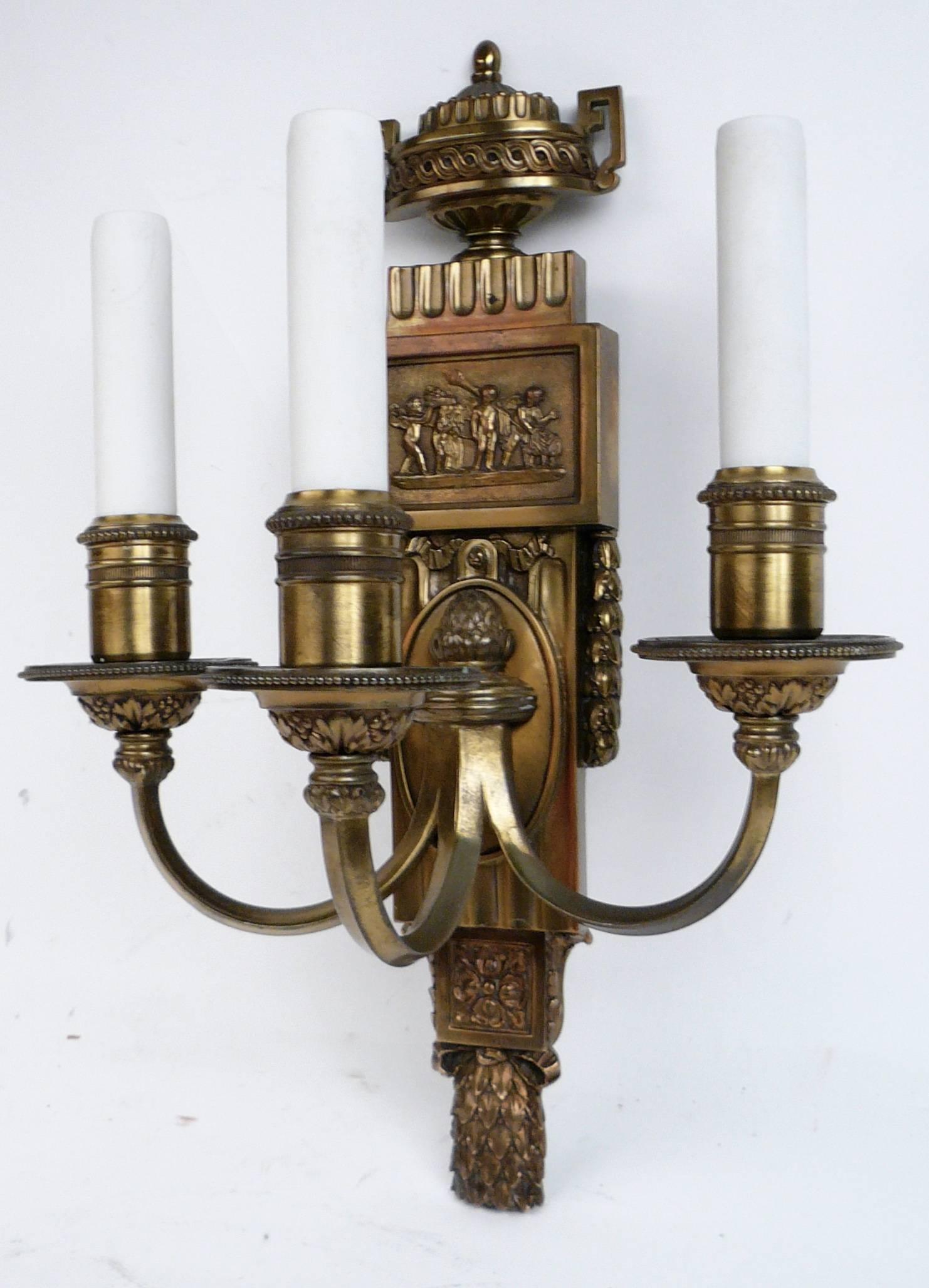 This handsome set of four Caldwell sconces feature Classical motifs, including acanthus and laurel leaves, urns, and Adam style mythological scenes with frolicking putti. These sconces have their original finish, and are newly wired.