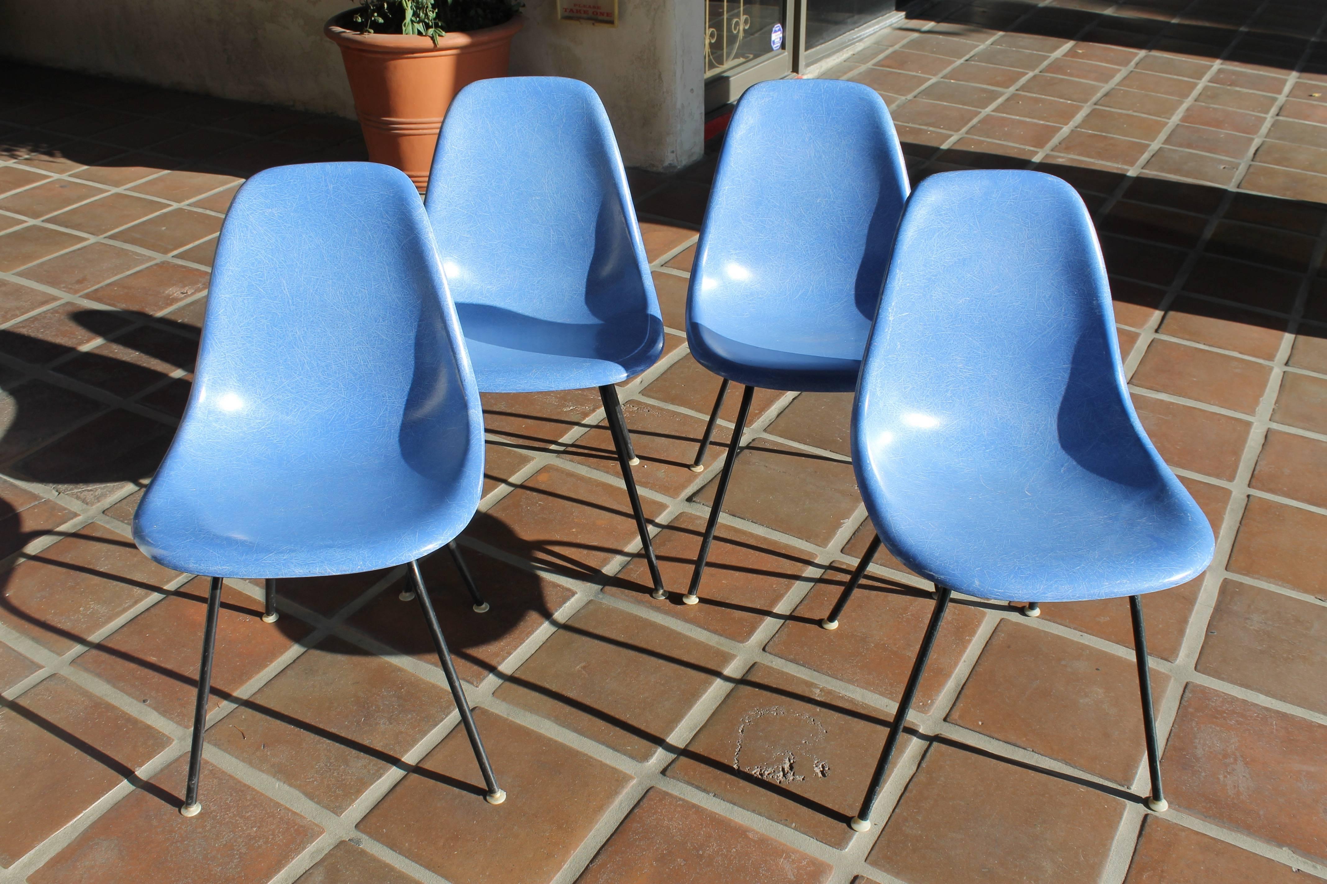 Set of four vintage Eames side chairs in blue fiberglass with black H-bases. All original, these four have always lived together. Bases are original to chairs. Signed with molded Herman Miller mark as well as paper labels. Ink stamp date on two of