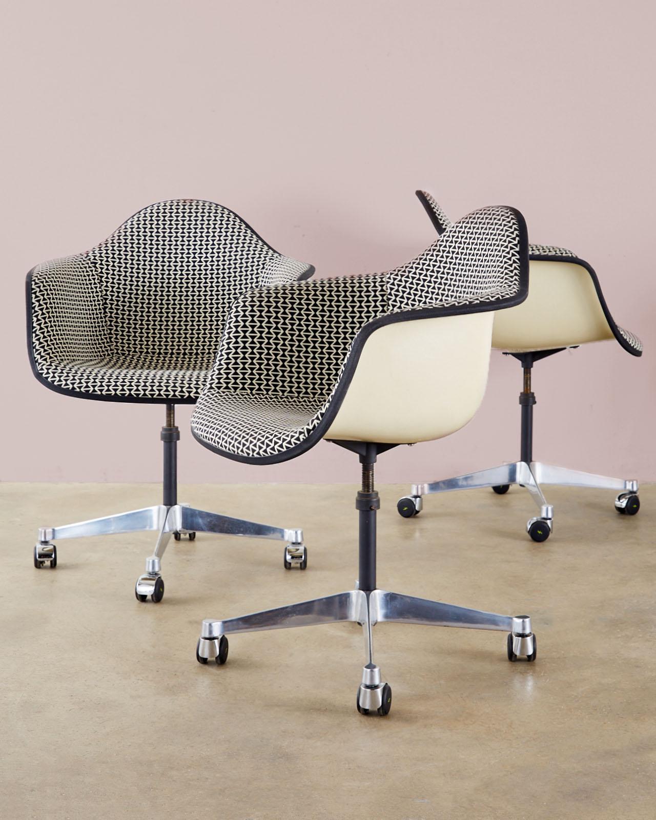 Dazzling mid-century set of four padded swivel chairs by Charles and Ray Eames for Herman Miller. The fiberglass shells are upholstered in a rare geometric black and white print with a black border. Supported by a four star polished swivel base