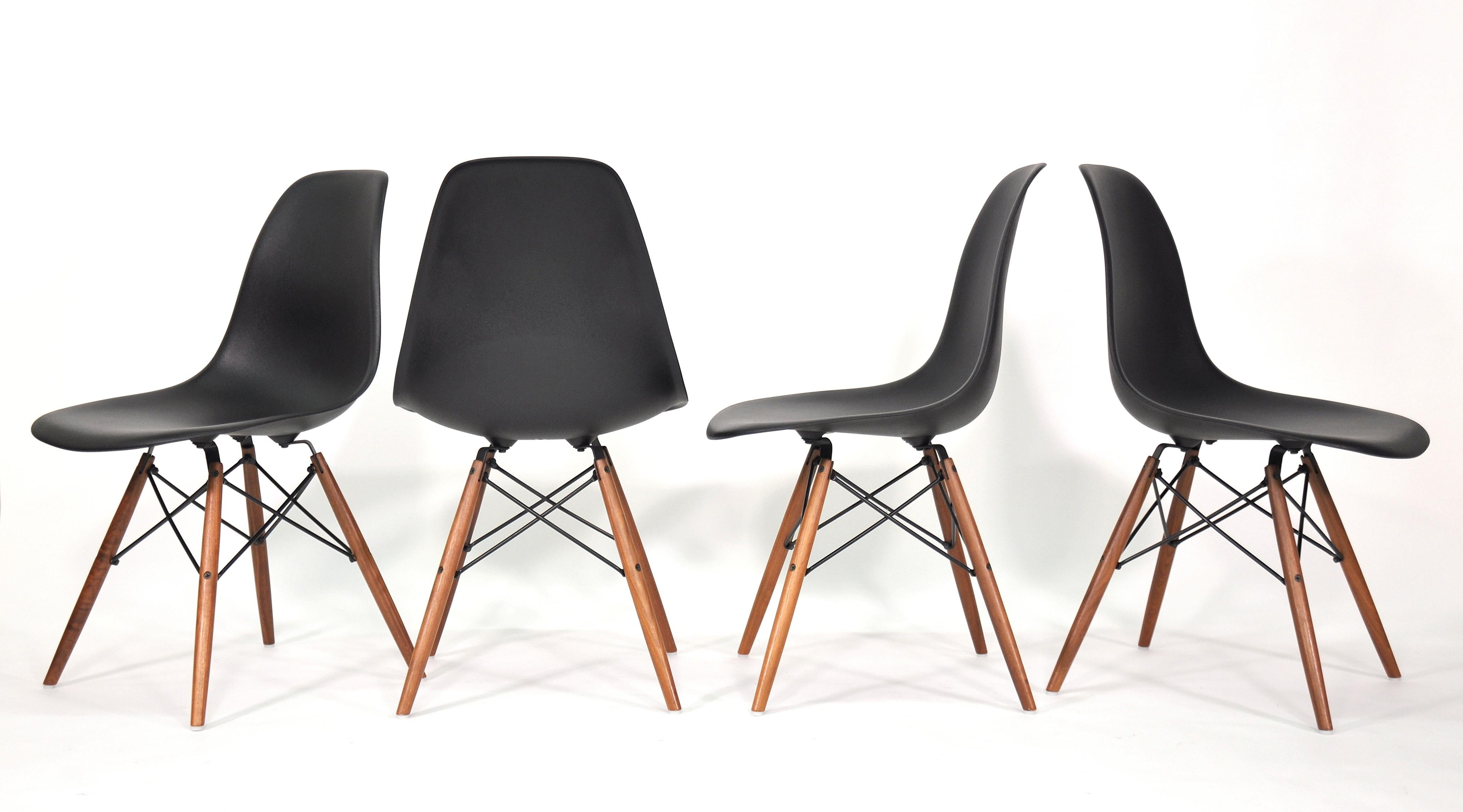A set of 4 DSW black shell chairs designed by Charles and Ray Eames for Herman Miller in the 1950s. The dining or side chairs feature a molded black shell and walnut dowel 