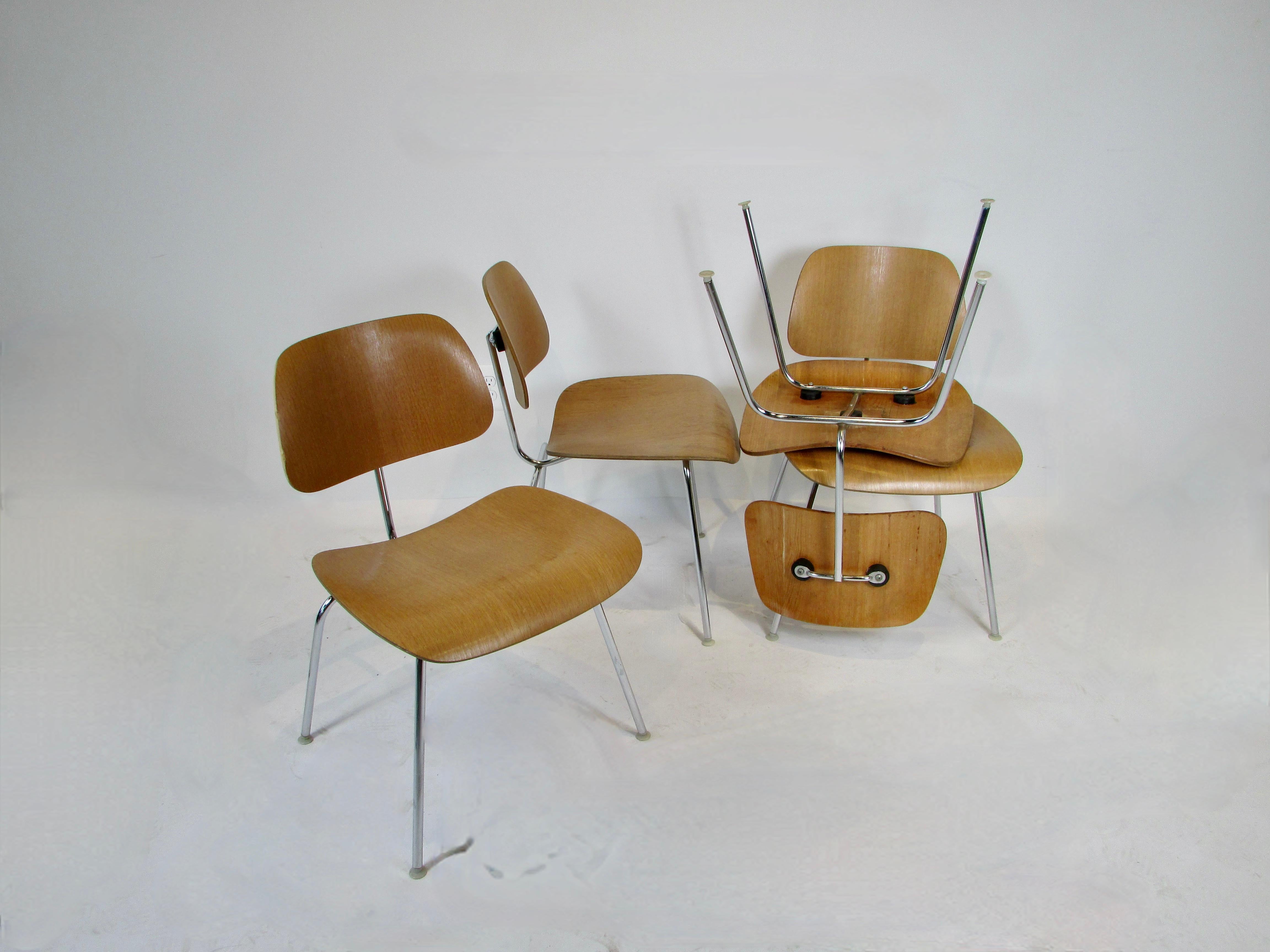 Set of four Eames for Herman Miller DCM chairs . Calico Ash grain laminate wood on chrome steel frames . Wood is in original finish which does show some wear , chrome frames are in fine condition . All glides are intact on the legs .  One chair