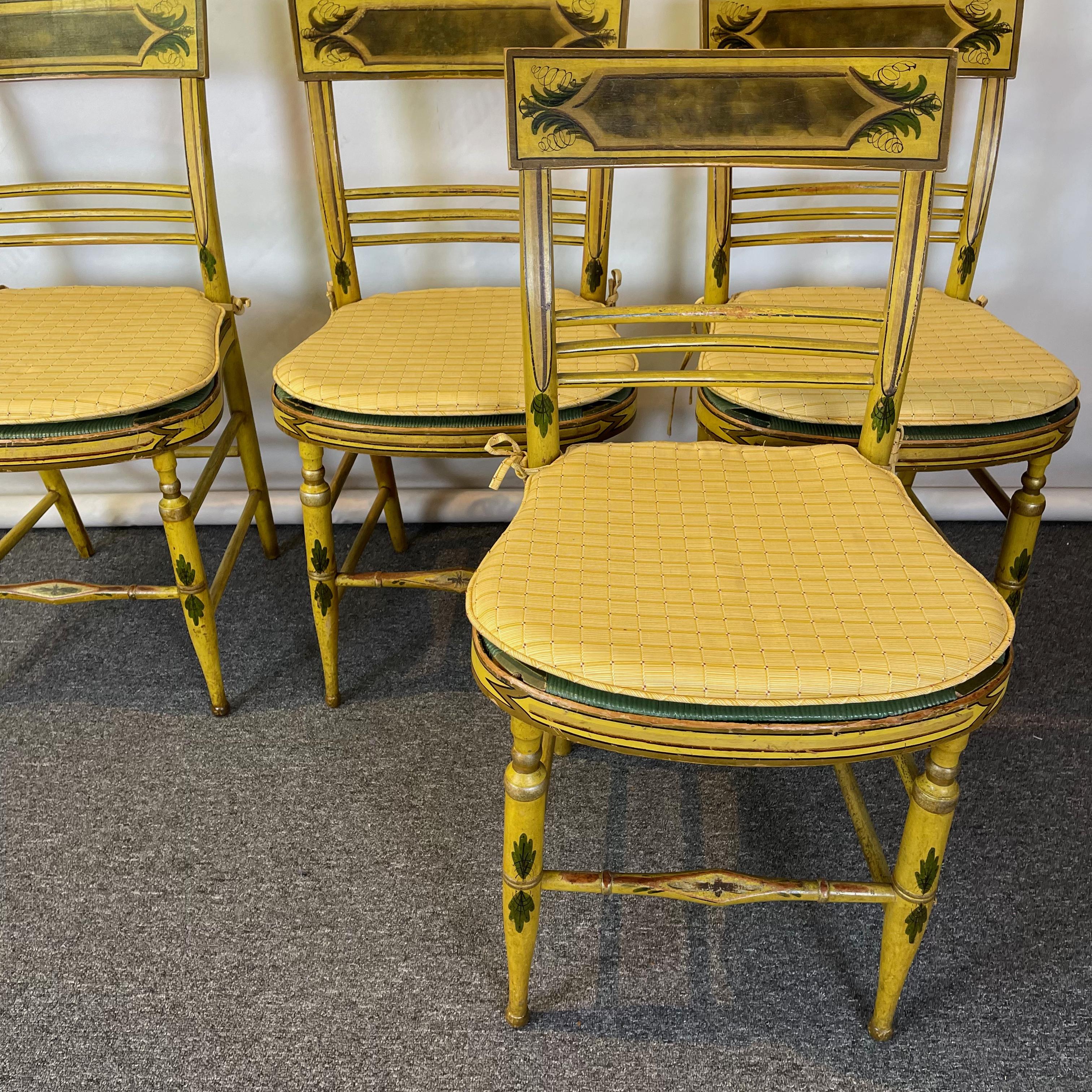 A set of four large and sturdy early 19th C. American fancy chairs in mustard yellow and additional paint decoration with green painted rush seats and loose upholstered cushions most likely made in coastal New Hampshire.