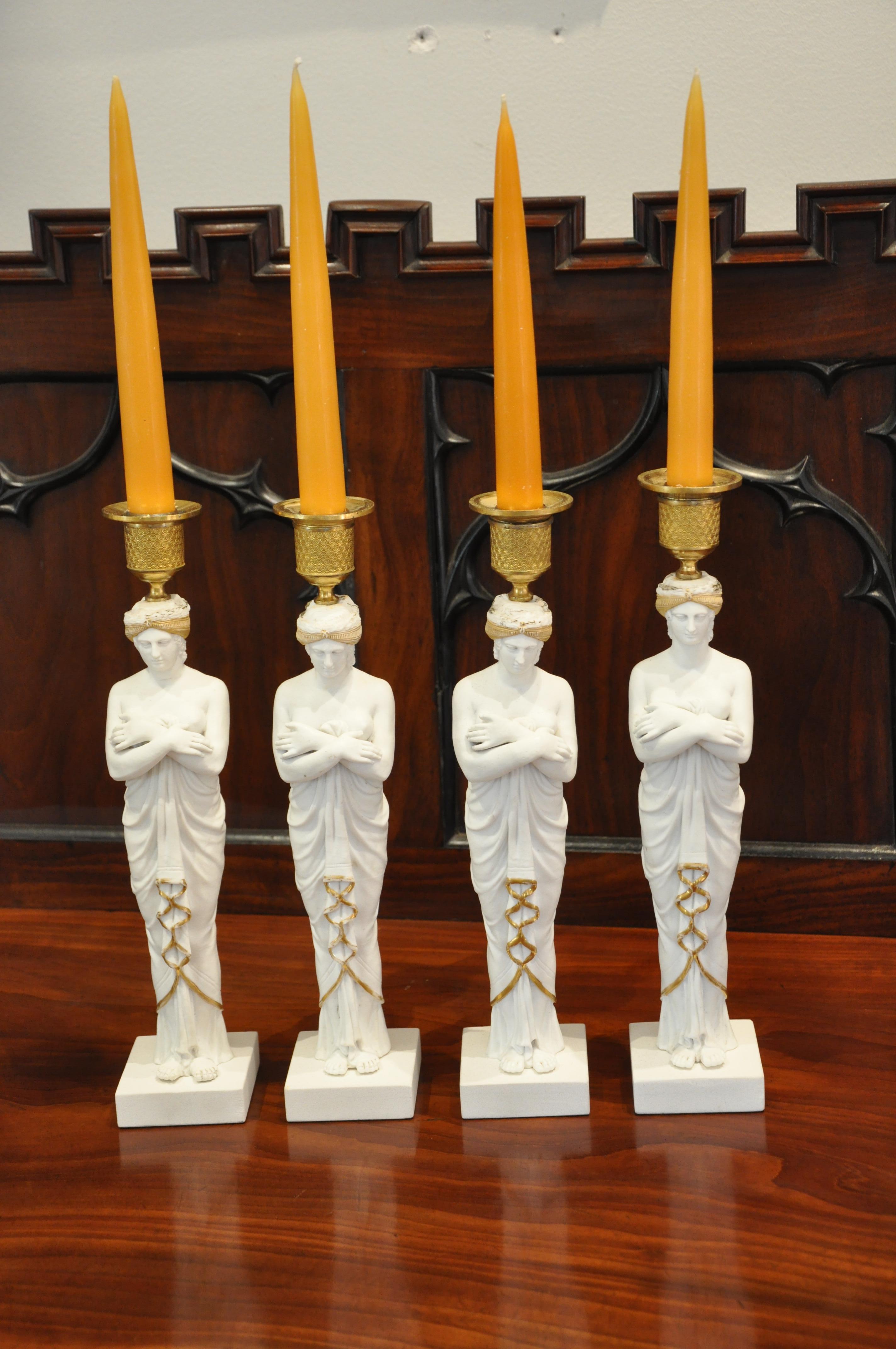 Set of four old Paris bisque porcelain caryatids as candlesticks

Early 19th century biscuit porcelain figural caryatids with arms crossed on bases with ormolu candle cups on head. Neoclassical or French Empire.