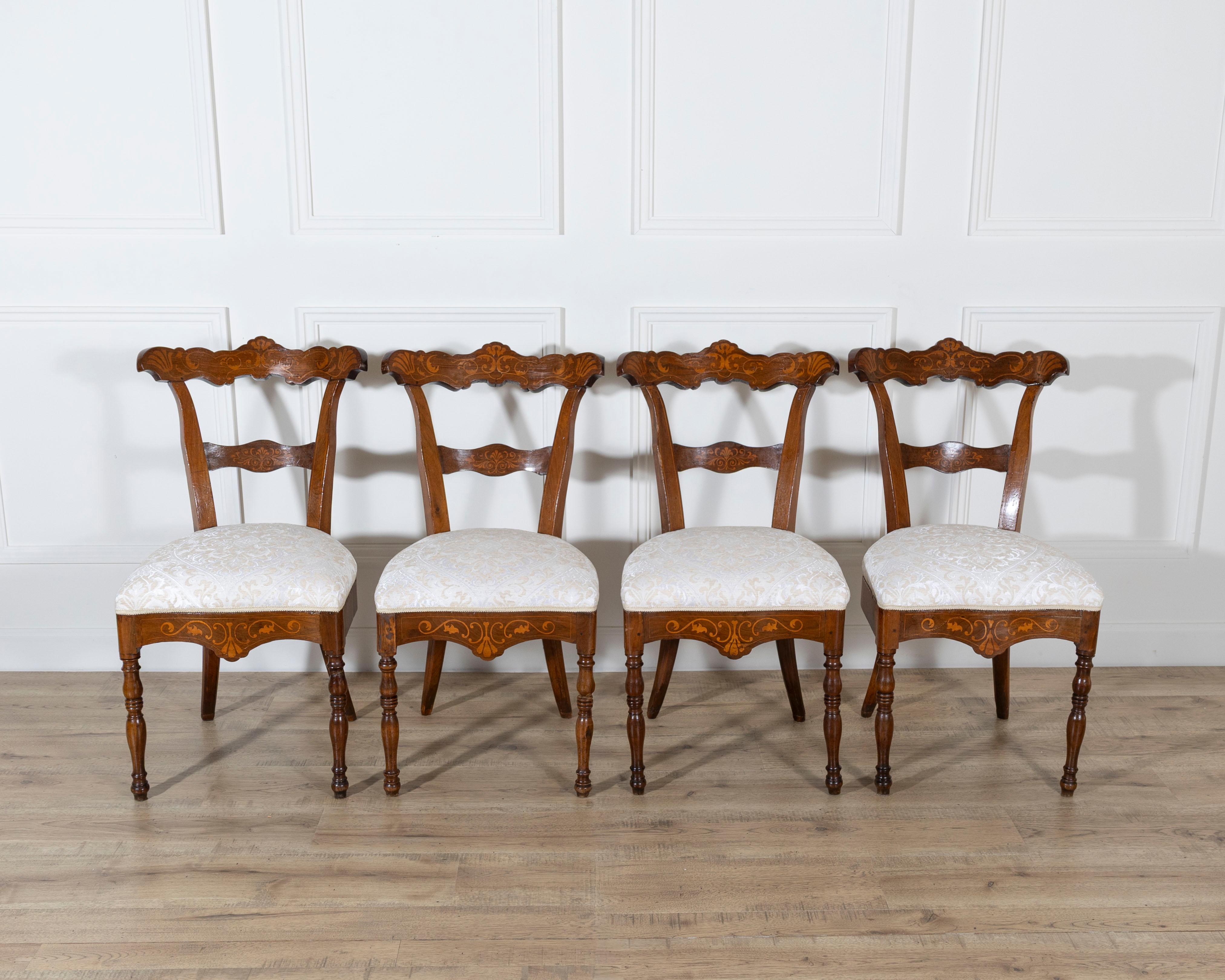A refined set of four Charles X dining chairs, masterfully crafted in the early 19th century from richly toned walnut with elegant fruitwood and maple inlays. Each chair exemplifies the lightness and harmony of the Charles X period, combining