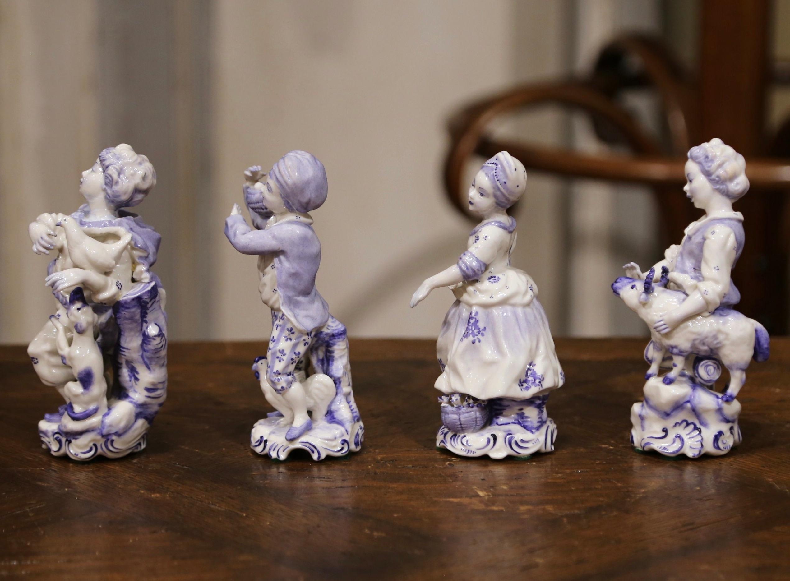Crafted in Holland circa 1920, the four faience sculptures depict peasant young beauties in traditional clothing. One woman has a duck and dog, another holding eggs with chicken, another with a goat and the last one with a basket of flowers. The