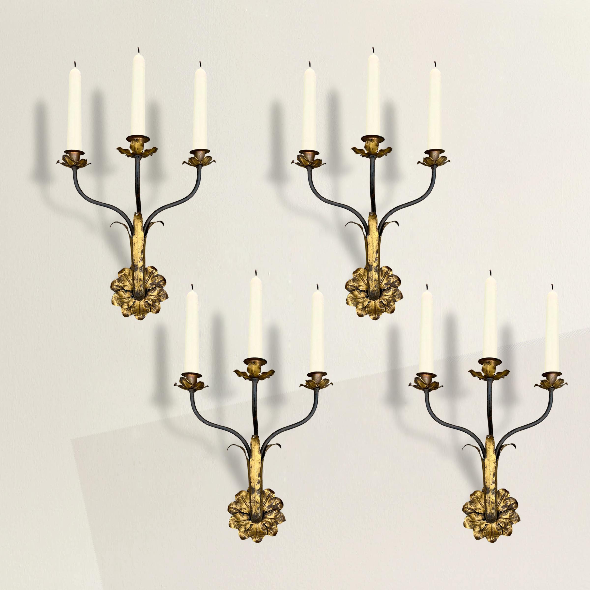 Elevate your interior with the timeless elegance of this set of four early 20th century Italian three-arm gilt iron candle sconces. Crafted with exquisite artistry, these sconces effortlessly blend classic design elements with a touch of opulence.