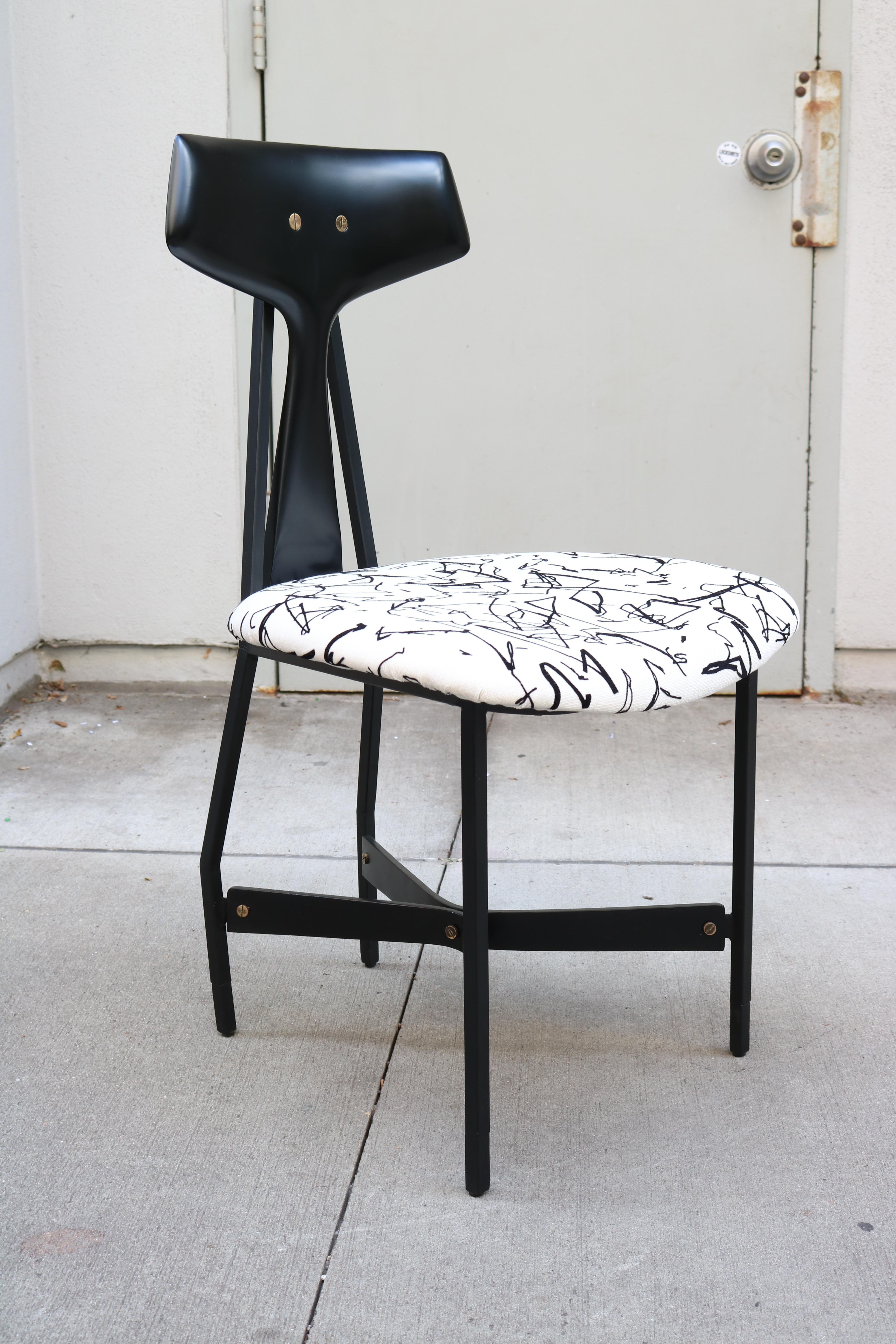A set of four modernist side chairs in ebonized wood and black metal. 