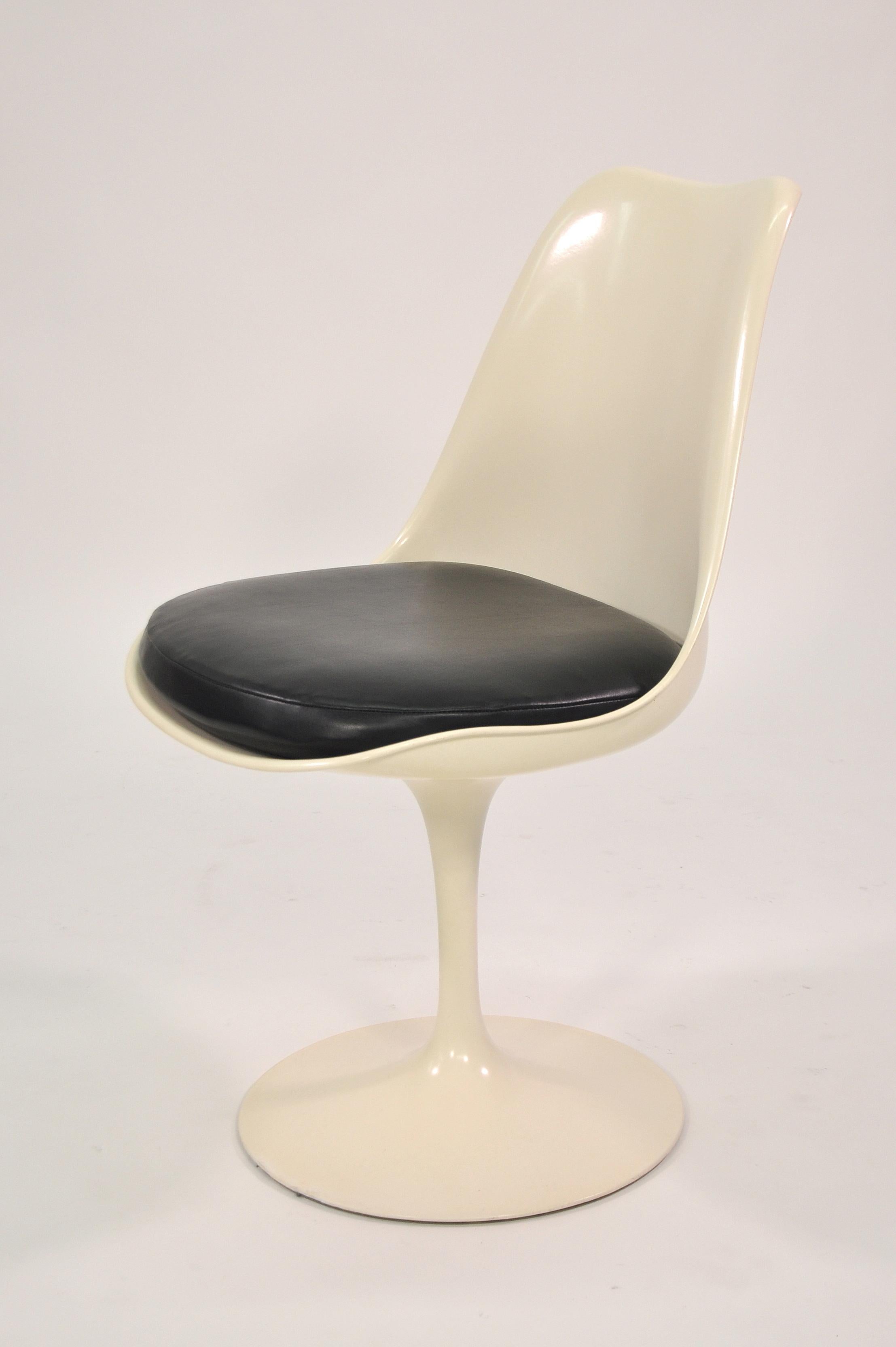 A vintage 1960s set of four Mid-Century Modern white Tulip dining chairs with black vinyl seats. The chairs have their original finish with beautiful patina. The Tulip chair is very comfortable and can also be used as an office chair. Eero