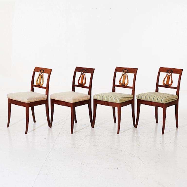 A set of four Empire mahogany chairs. Veneer and solids in mahogany, openwork back tray with lyric decorations. Seat height is 48 cm. Seats are in original upholstery. We can reupholster as COM (Customer's Own Material) or in one of our stocked