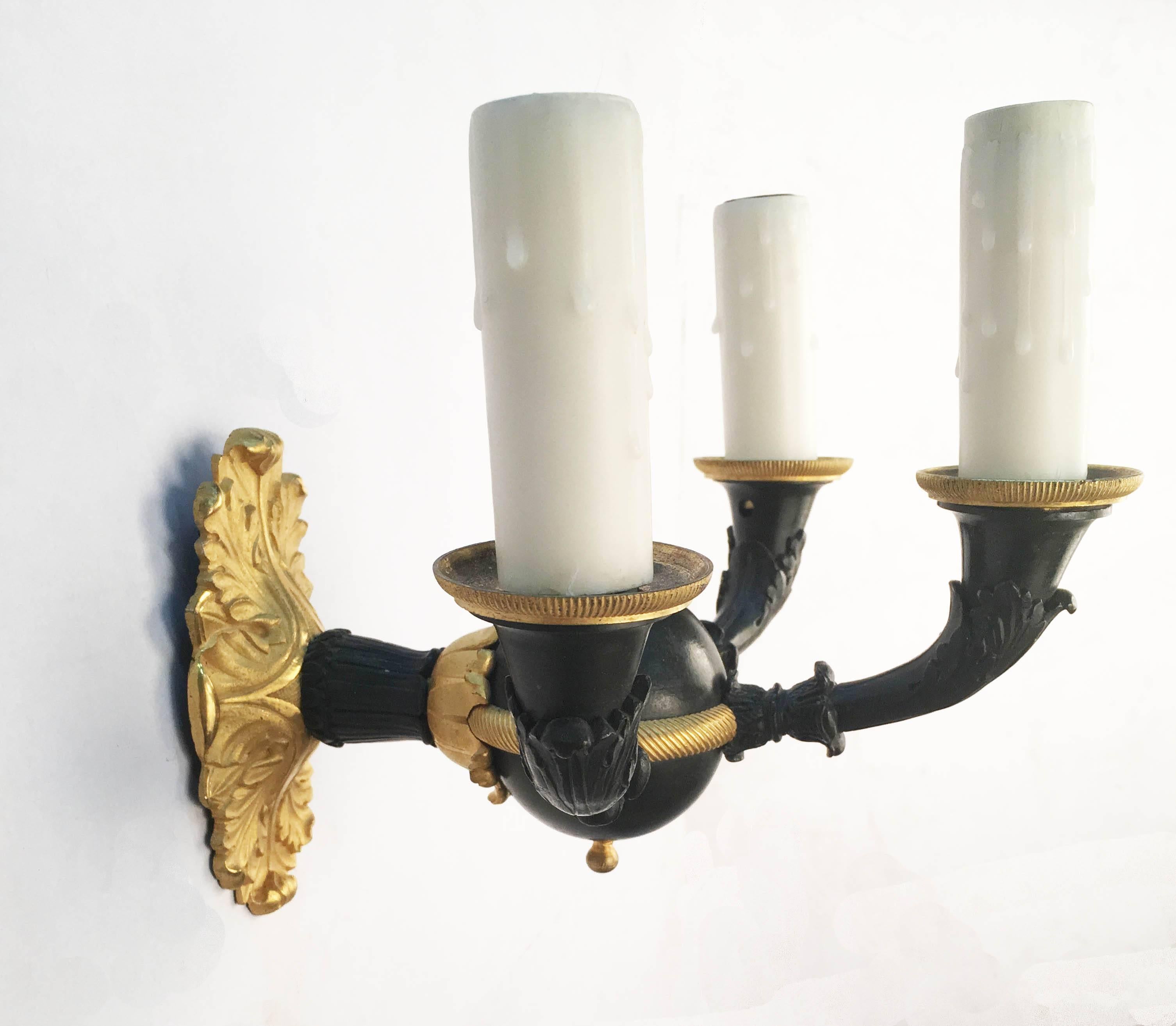 Set of four French Empire style  cast bronze three-arm wall sconces. The
oval cast gilt bronze back plate, with stylized acanthus leaf design, supporting a gilt banded dark patinated sphere set with three cast arms with acanthus leaf details ending