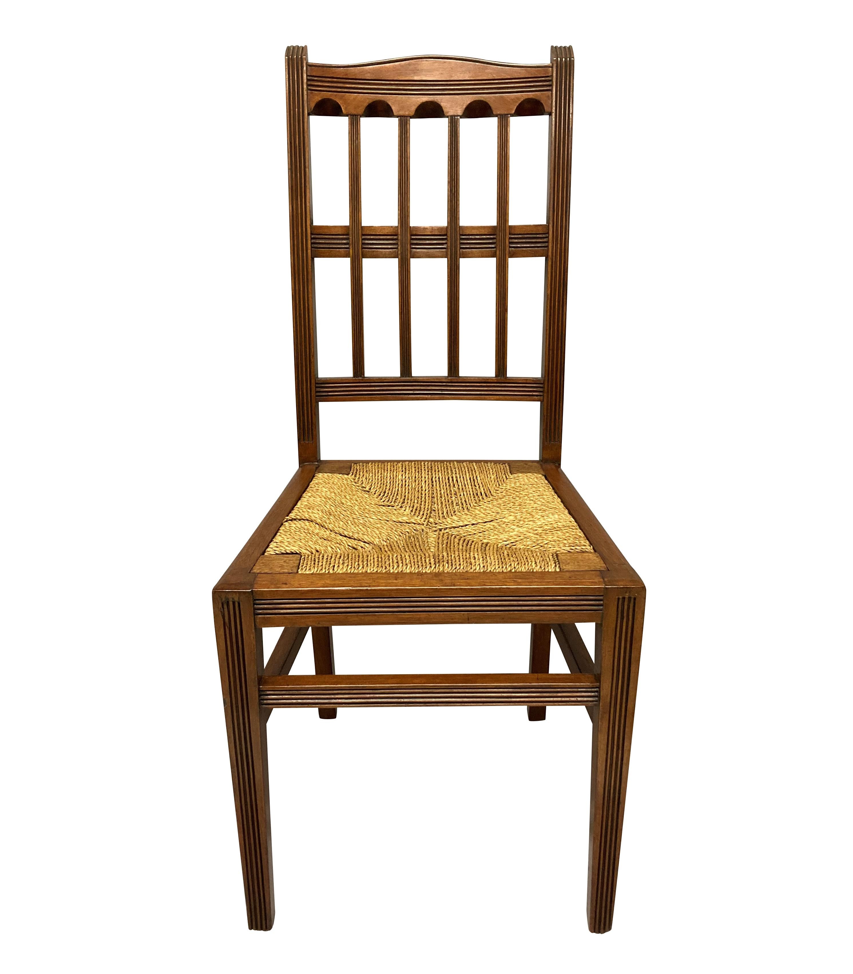 A set of four English mahogany Aesthetic Movement dining chairs, with rush seats.