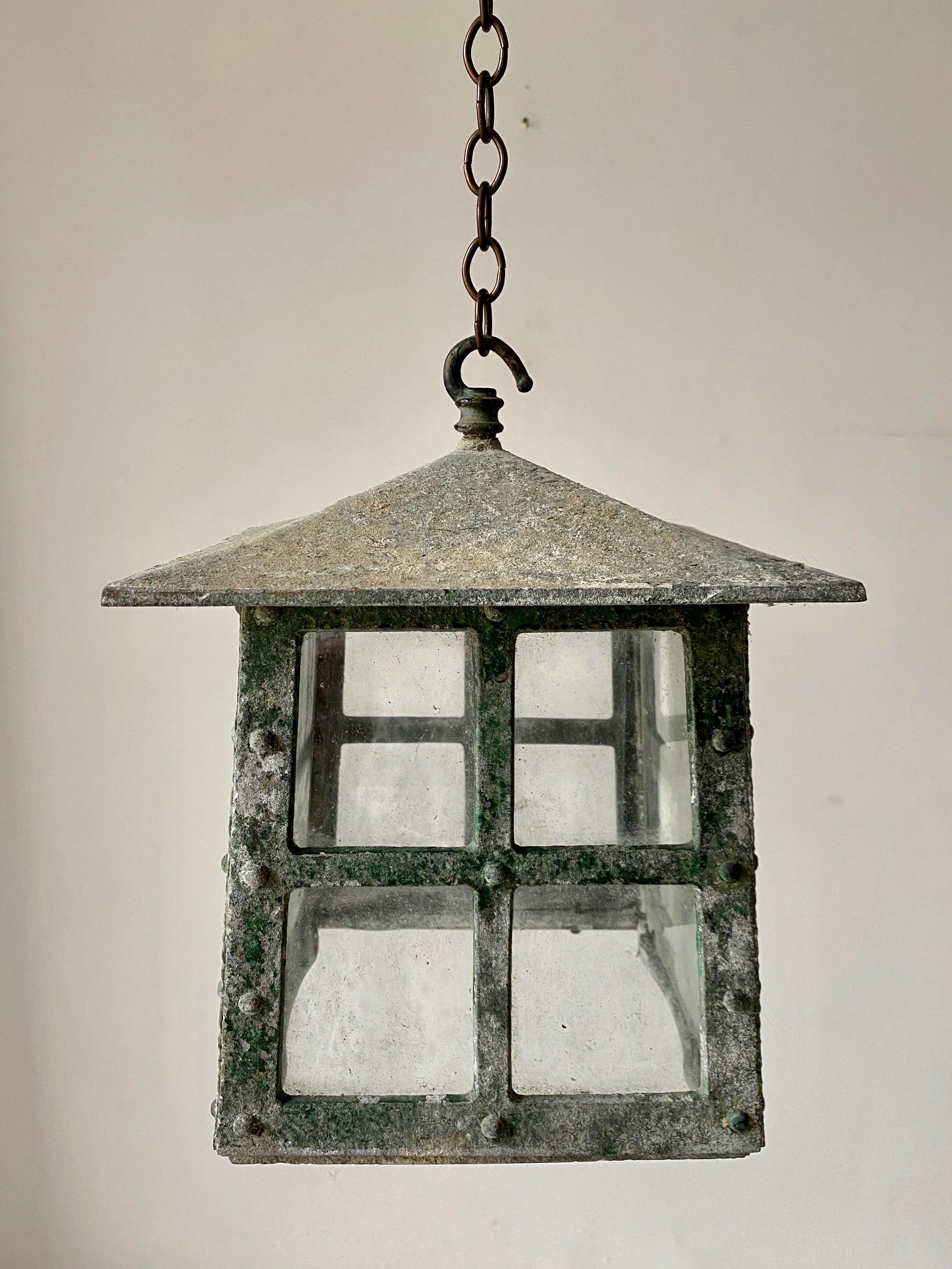 A set of four metal alloy, previously painted, Arts & Crafts lanterns. Riveted body with a typical pagoda form. Original glass. Fabricated circa 1930 in England.
The fabulous patina shows a mottled green, from the paint of yesteryear. Hook fittings
