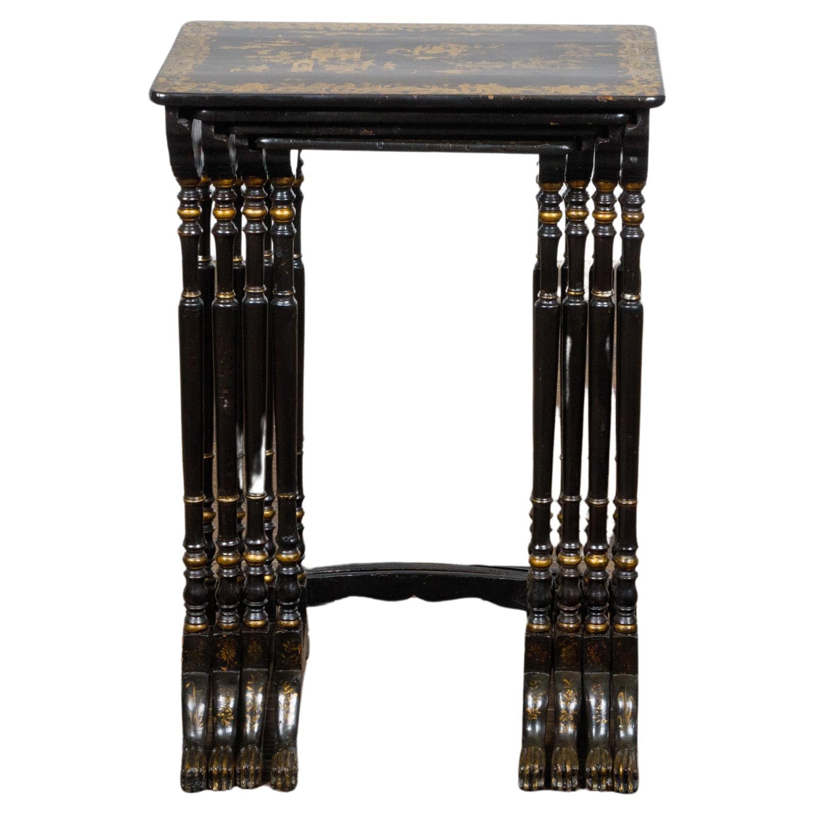 A set of four English black and gold nesting tables from the 19th century with Chinoiserie décor, slender turned legs and bow front stretcher. This exquisite set of four English nesting tables from the 19th century features a stunning black and gold
