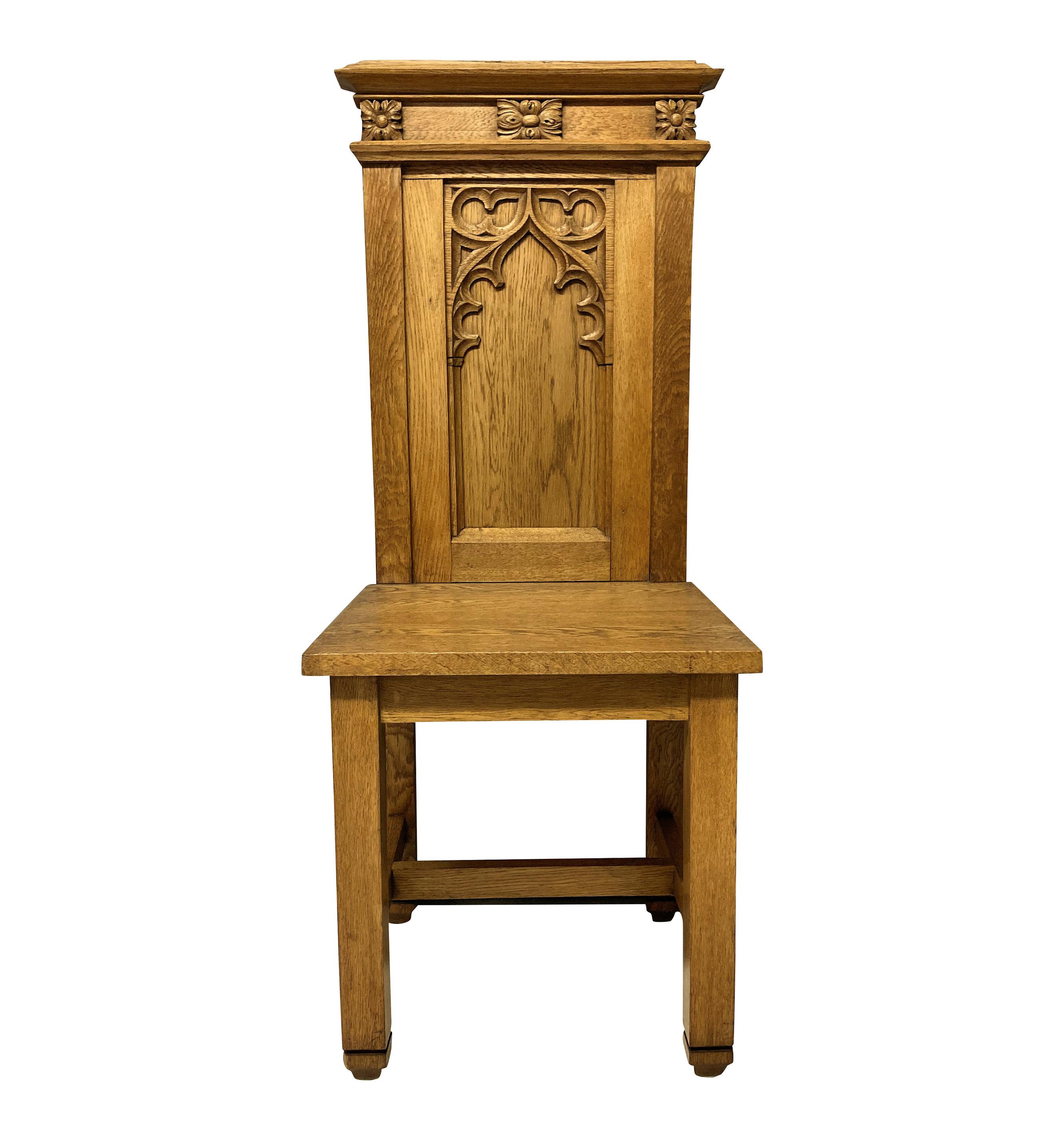 A set of four English pale oak Gothic hall chairs, with crisp carving.