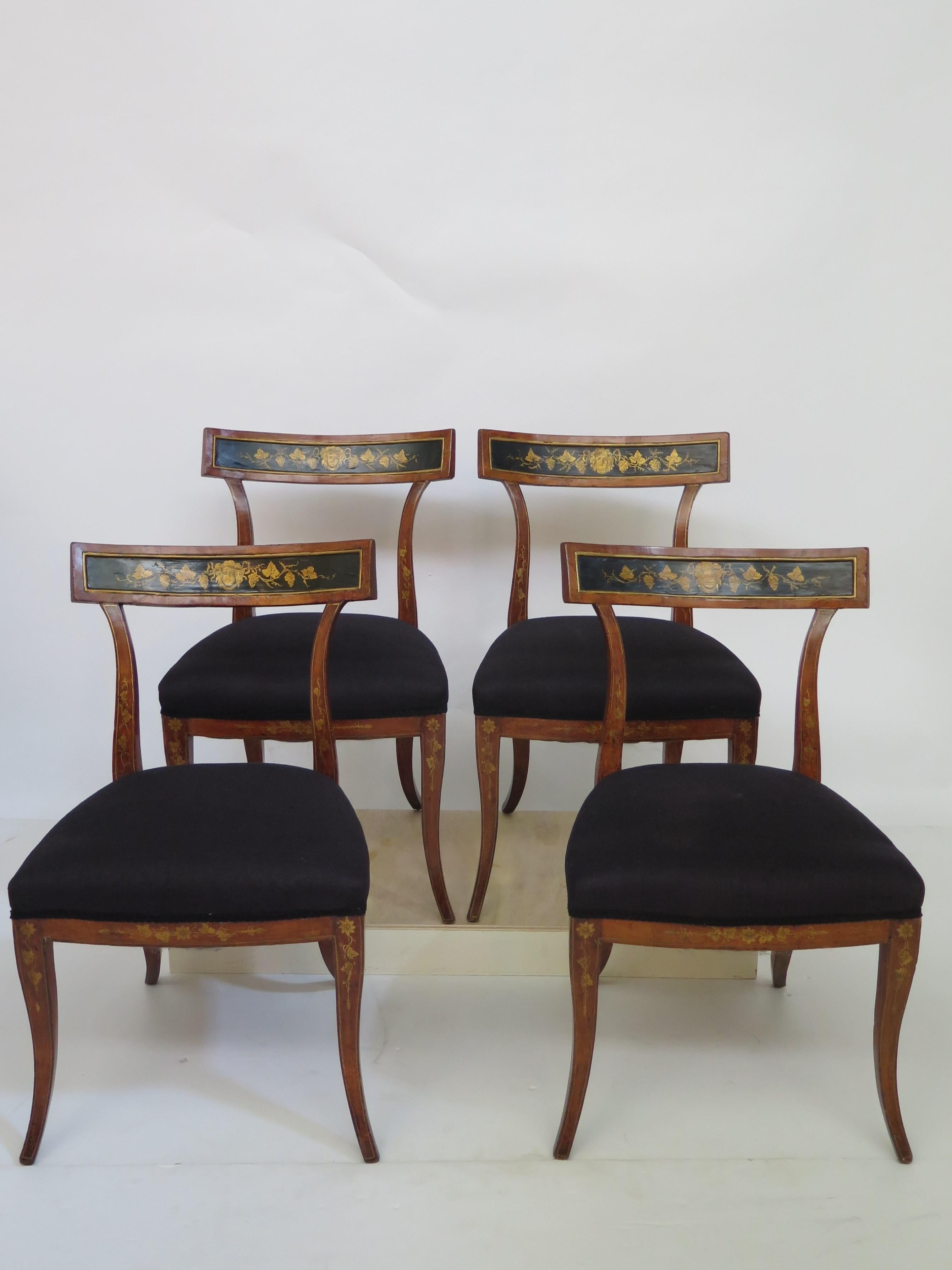 A set of four English Regency period sabre leg dining chairs. 
With classic Regency styling this fruitwood set offers black upholstered seats.
The centre back rail is well formed and has painted in the chinoiserie style, black and gold picture