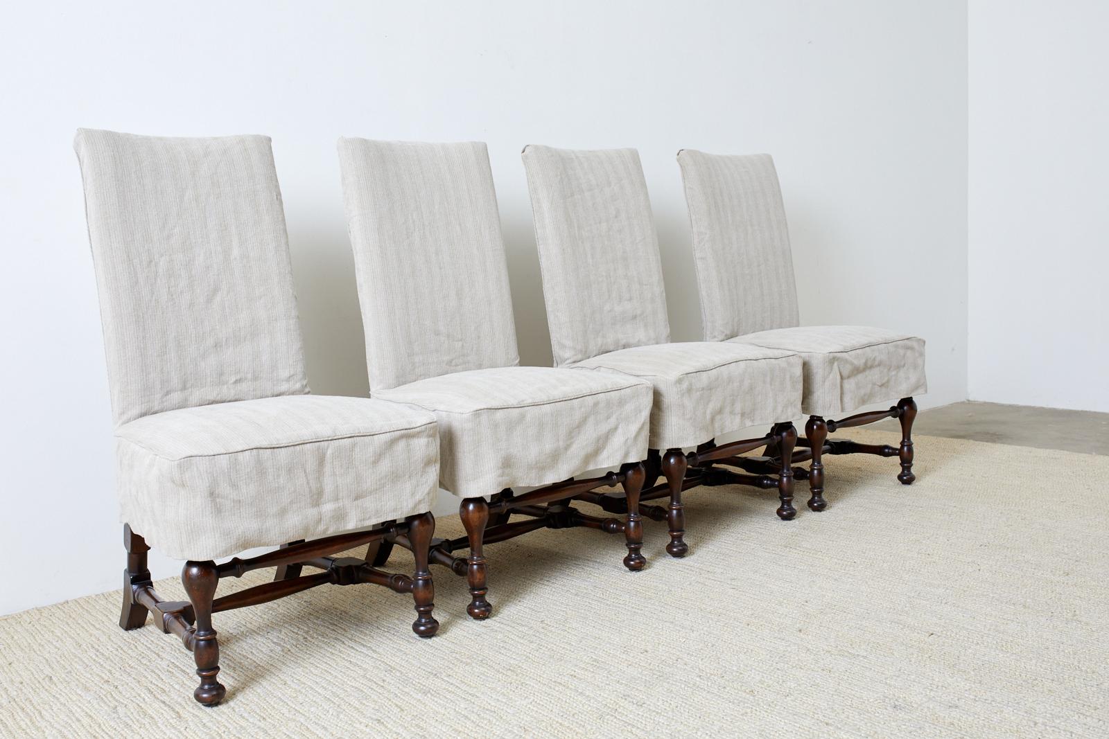 Set of four English style walnut dining chairs featuring a linen slipcover. The chairs have a hardwood frame with distinctive turned supports and stretchers made in the William and Mary taste. The frames are upholstered with a striped silk pattern