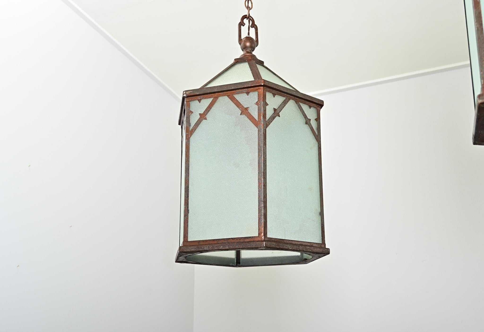 Set di quattro lanterne vintage in vetro e acciaio del XX secolo provenienti dall'Inghilterra. Questo sorprendente insieme di apparecchi di illuminazione ha un'influenza vagamente gotica nella sua forma esagonale, fatta di lastre di vetro