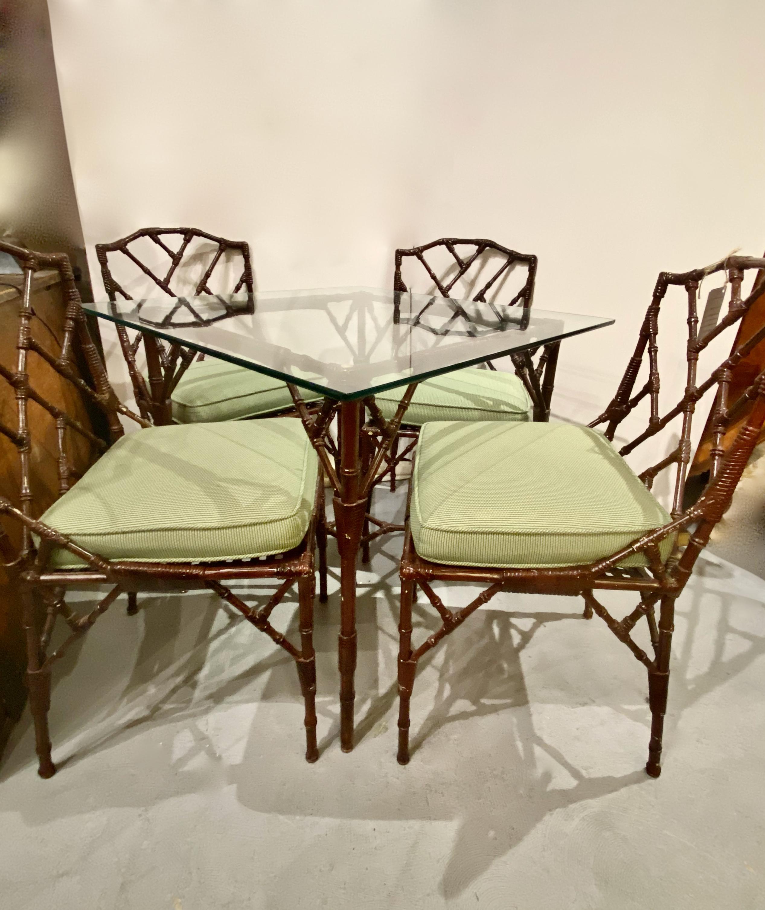 This is an unusual set of 4 Chinese Chippendale cast aluminum side chairs in the Chinese Chippendale style together with a matching cast aluminum faux bamboo table with a glass top. The level of detail in the casting of the chairs and the table is