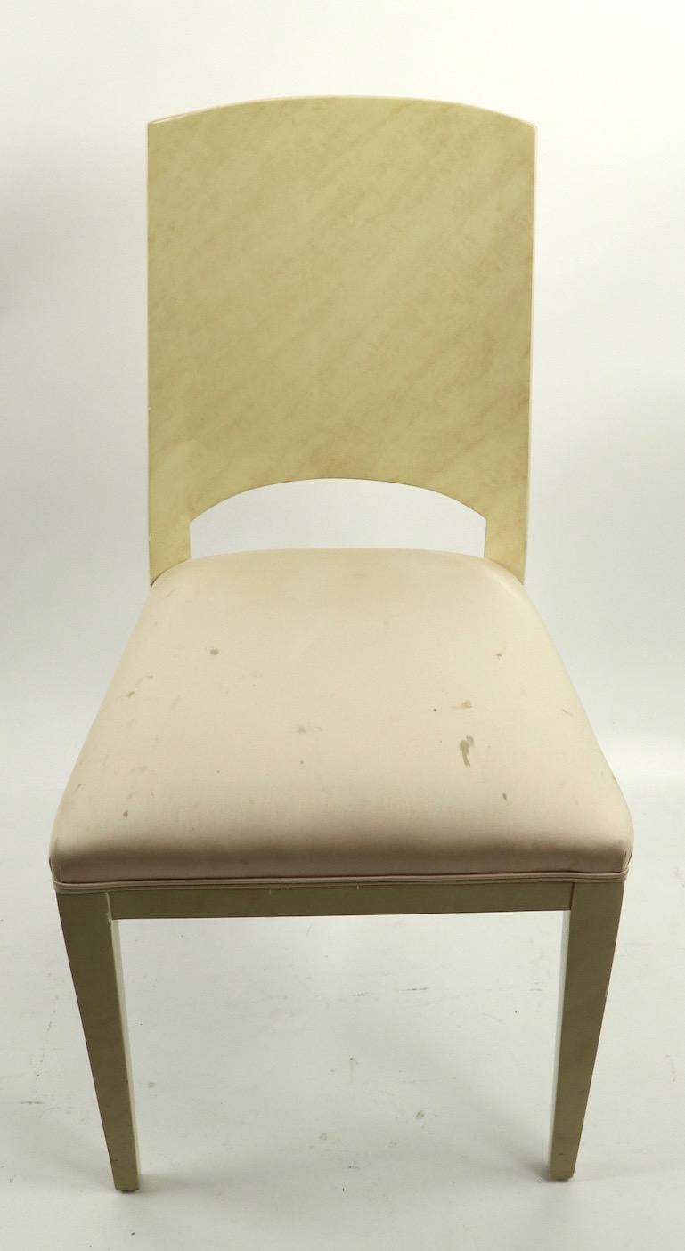 Set of our lacquered paper faux skin dining chairs in very pale yellow with off white fabric seats, upholstery has stains etc. The curved backrest section adds a nice design element. Stylish Art Deco Revival chairs, in the manner of Karl Springer,