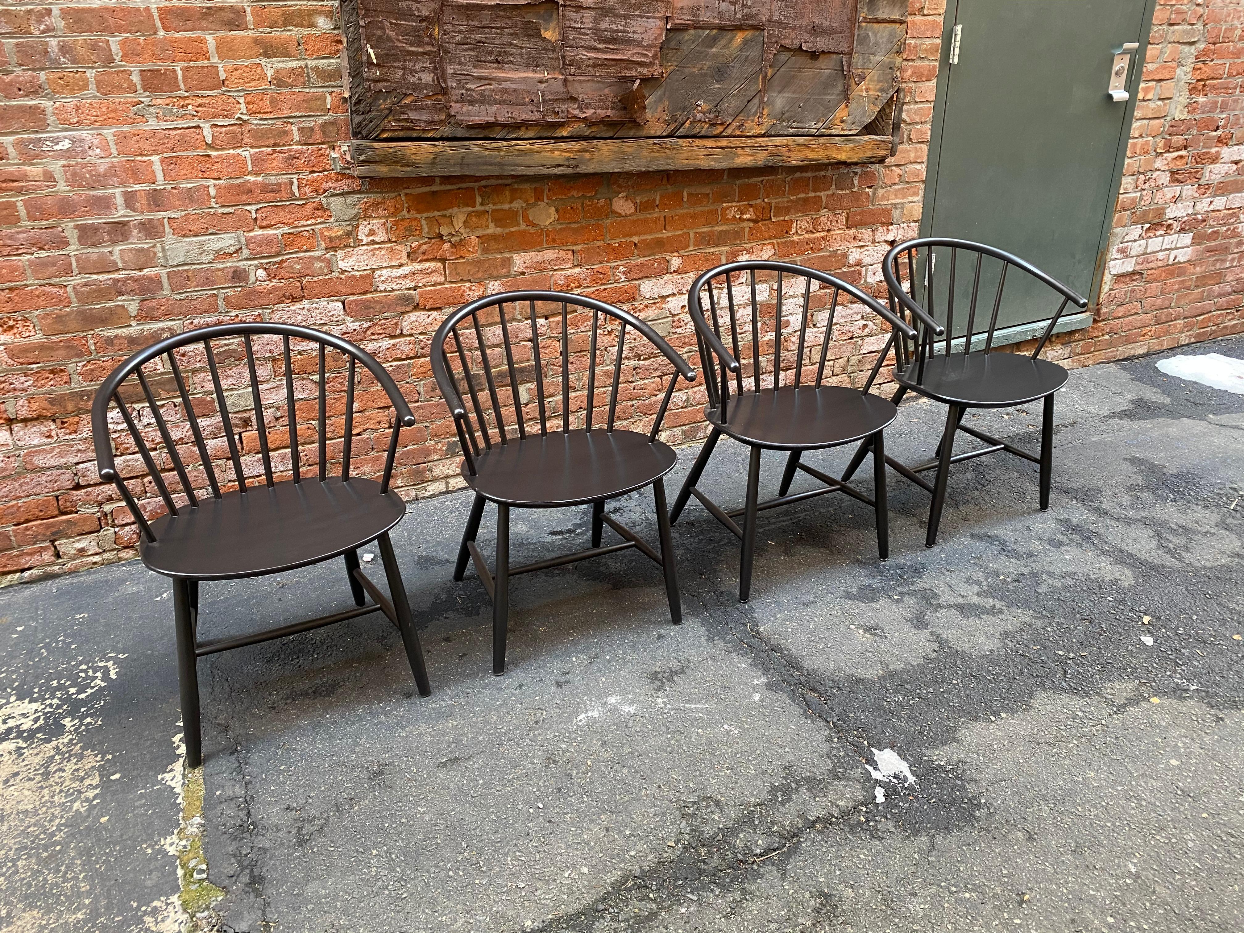 Set of four Ejvind A. Johansson designed spindle back chairs. Two are signed with the silver foil FDB Mobler, Danish control label. Good older restored black lacquer with some scratches and losses due to age and use. These elegant chairs feature a