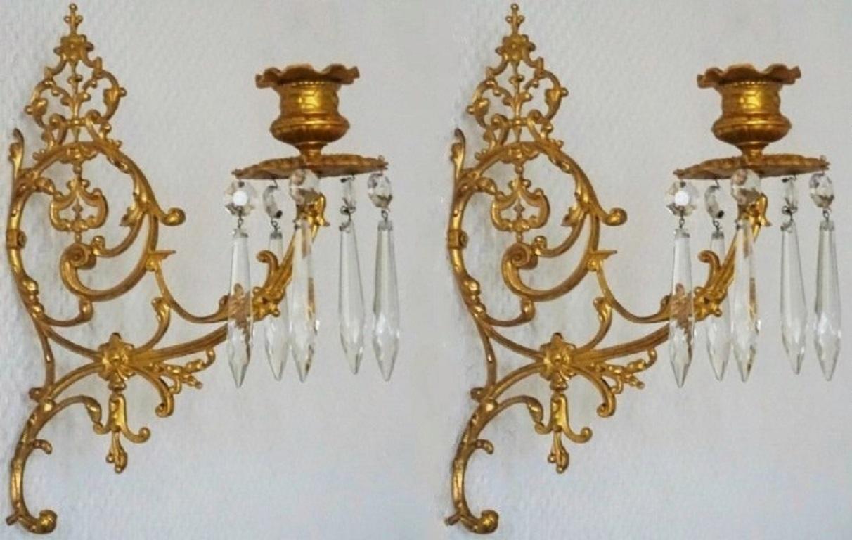 An extremely elegant and high quality set of four Louis XVI period candle wall sconces of doré bronze (fire-gilded bronze), wonderfully elaborate in fine and precise detail, decorated with long crystal icicle prisms, France, late 18th century. 
The