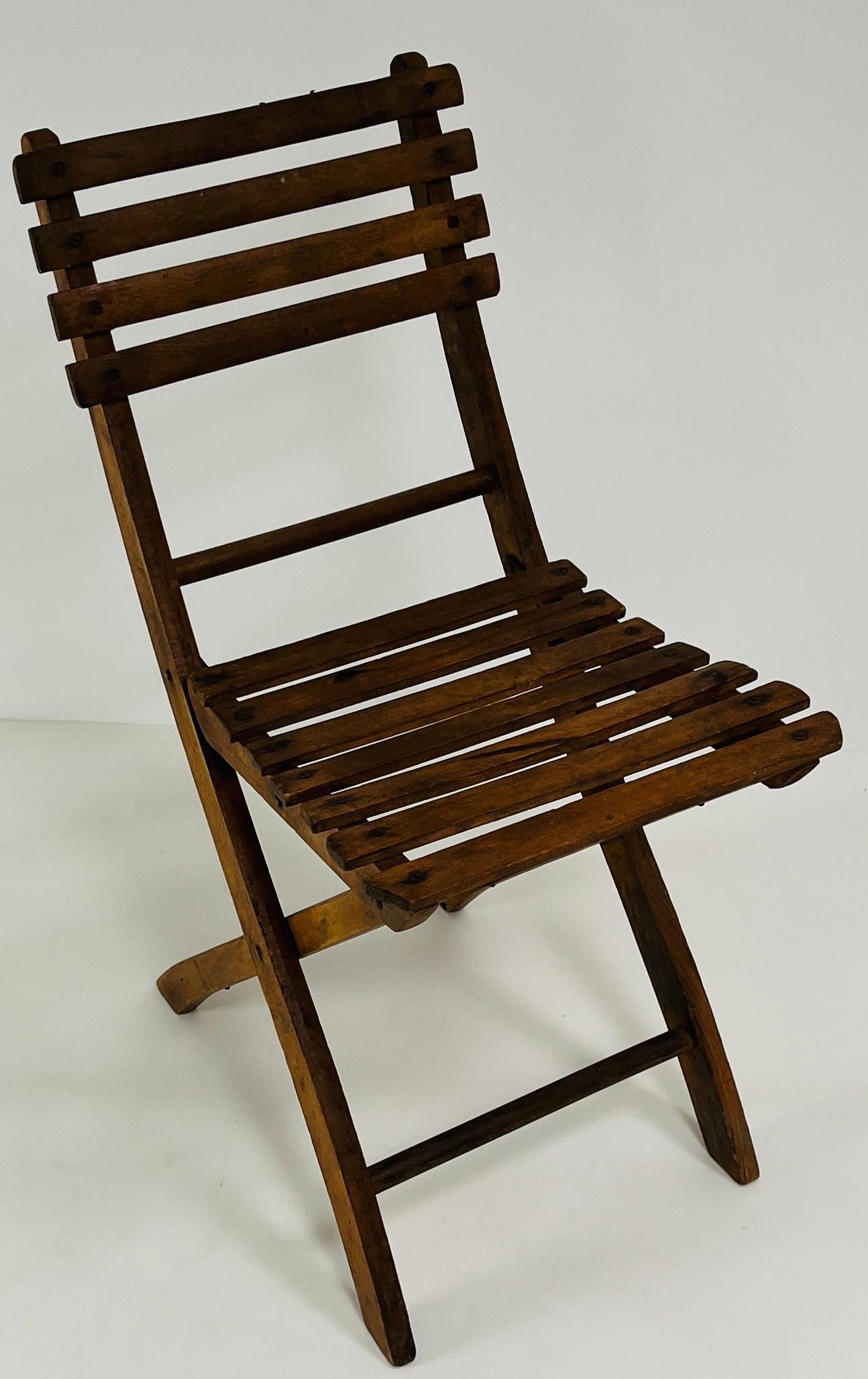 A rare ensemble of four antique French folding chairs, expertly crafted from solid oak. Each chair features a gracefully aged patina and a timeless slat construction across both the seat and backrest, highlighting rustic elegance and utilitarian