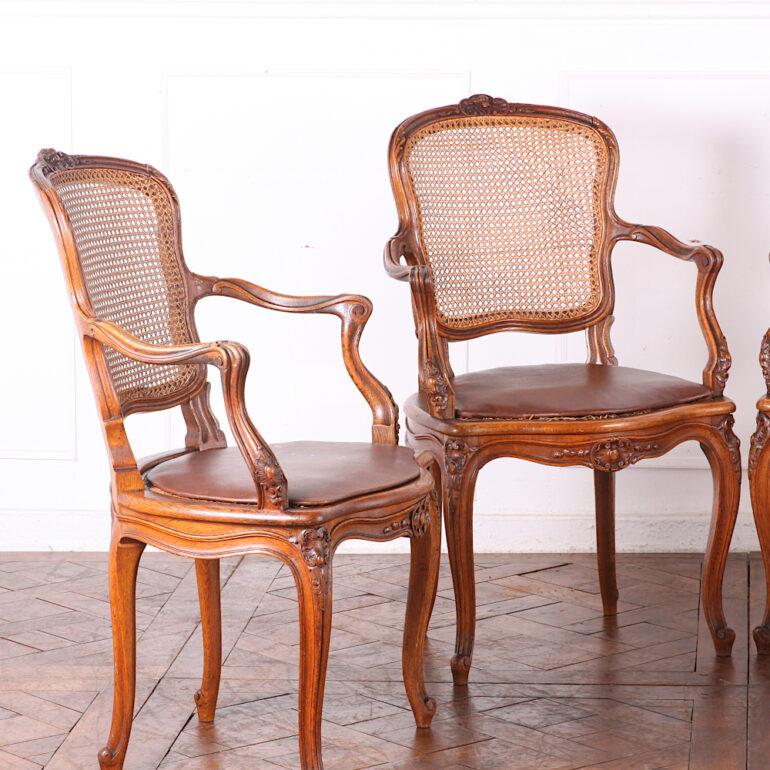 Set of four French carved oak Louis XV style bergeres or open armchairs with caned seats and backs. 

 