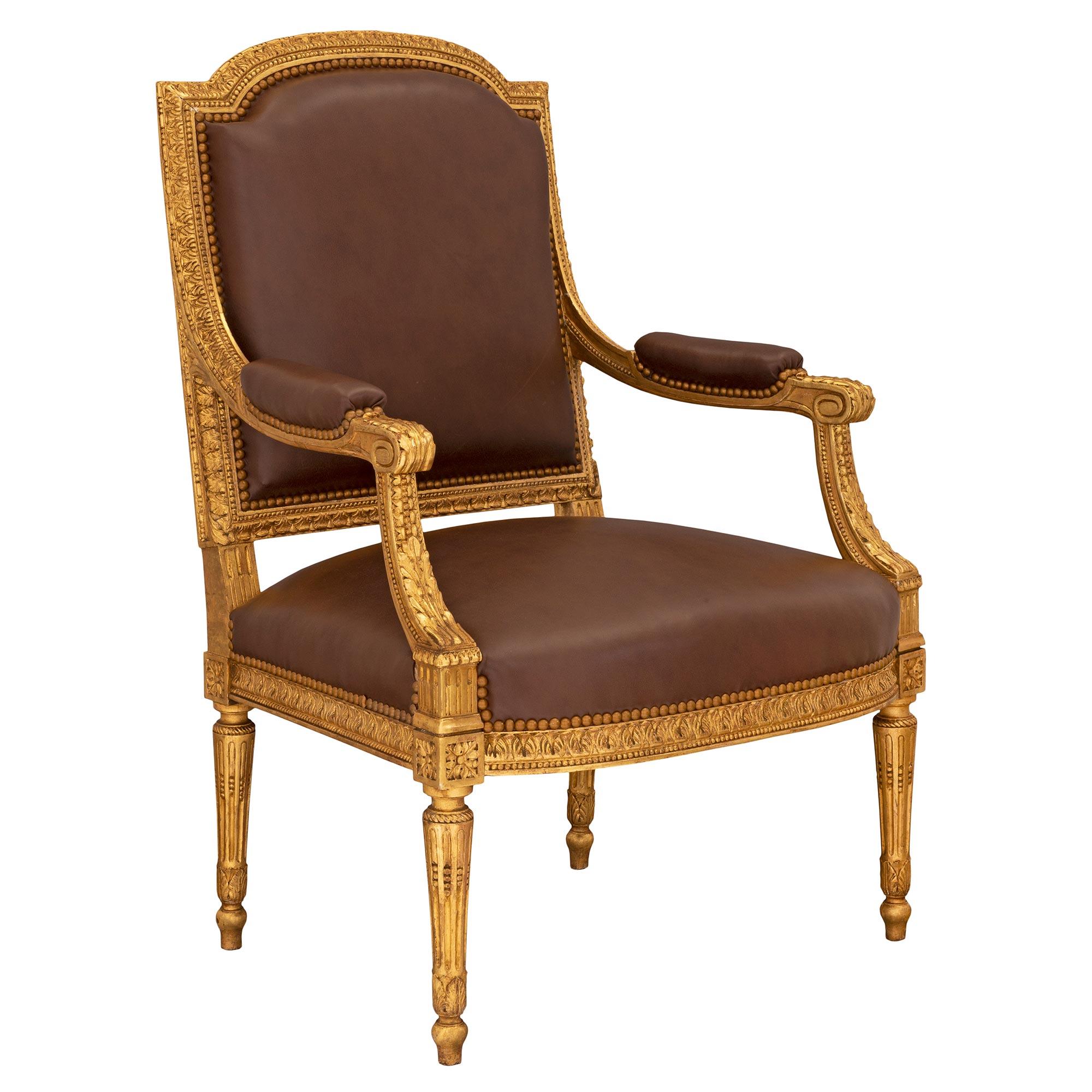 Un remarquable et très élégant ensemble complet de quatre fauteuils en bois doré de style Louis XVI du XIXe siècle. Chaque chaise repose sur des pieds circulaires fuselés et cannelés, des pieds en forme de topie, des feuilles finement sculptées et
