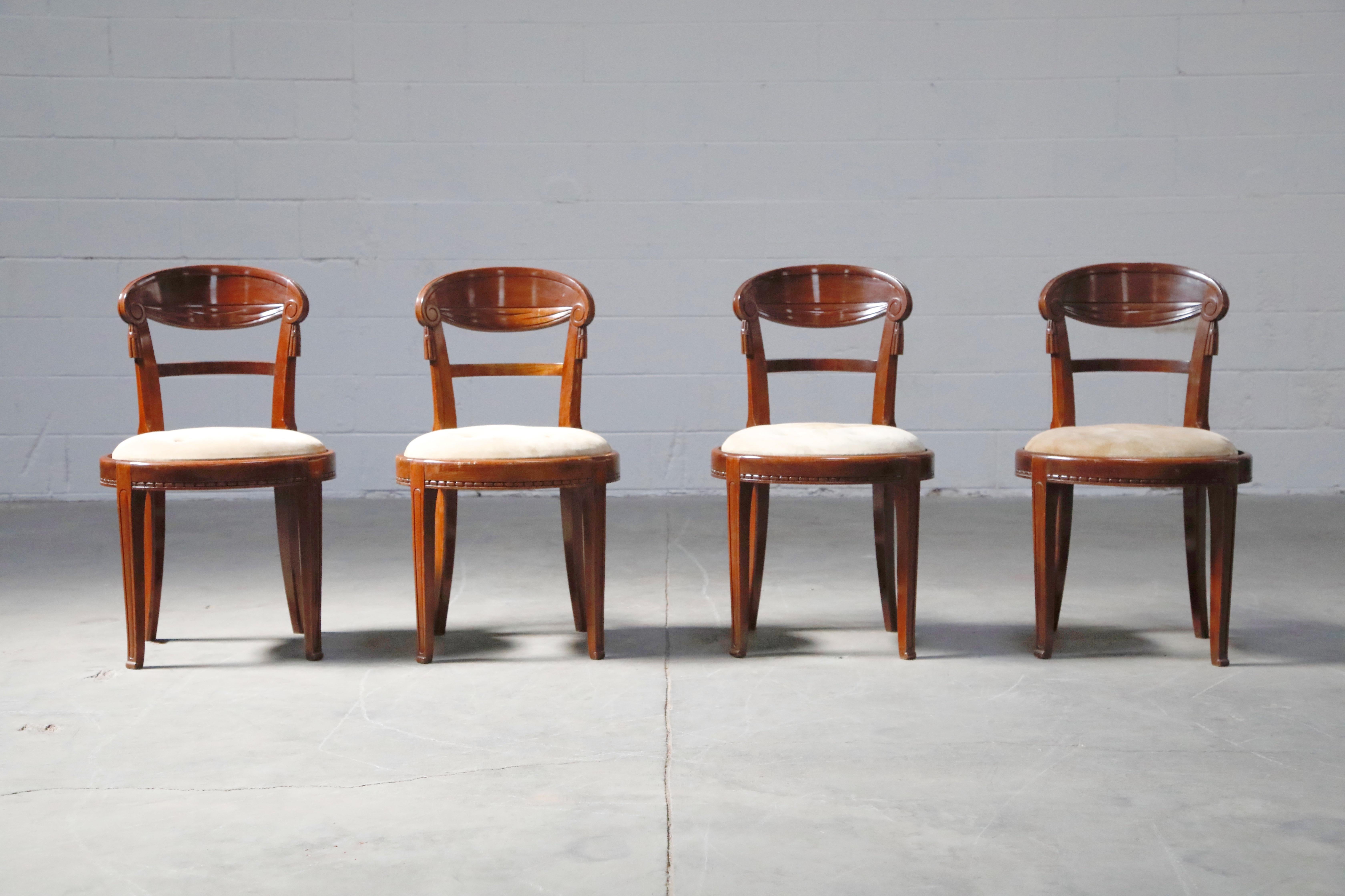 A superb suite of four French Art Deco Mahogany dining chairs with intricate wood detailing and suede upholstery, attributed to Sue et Mare, circa 1920s. 

The deep luxurious mahogany frames have curved seat backs with carved scroll ends and faux