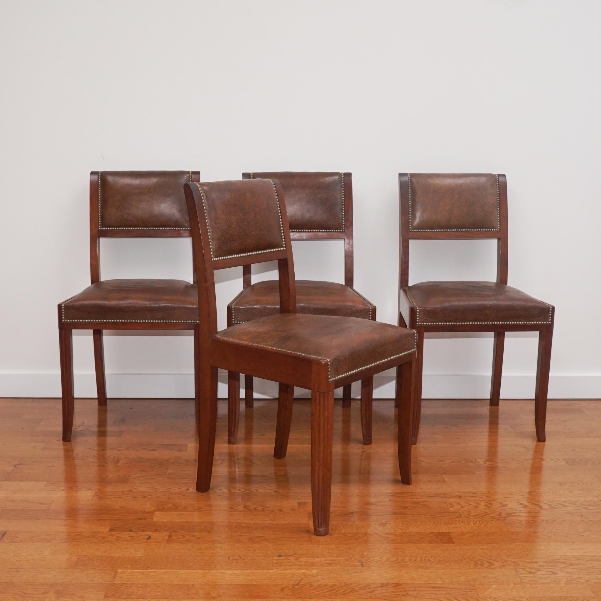The set of four French Art Deco side chairs, shown here, have been recently restored and freshly polished. Featuring rich, brown leather seat and back rests, each chair is accented with brass nail head trim and detailed with fluted front legs. Sold