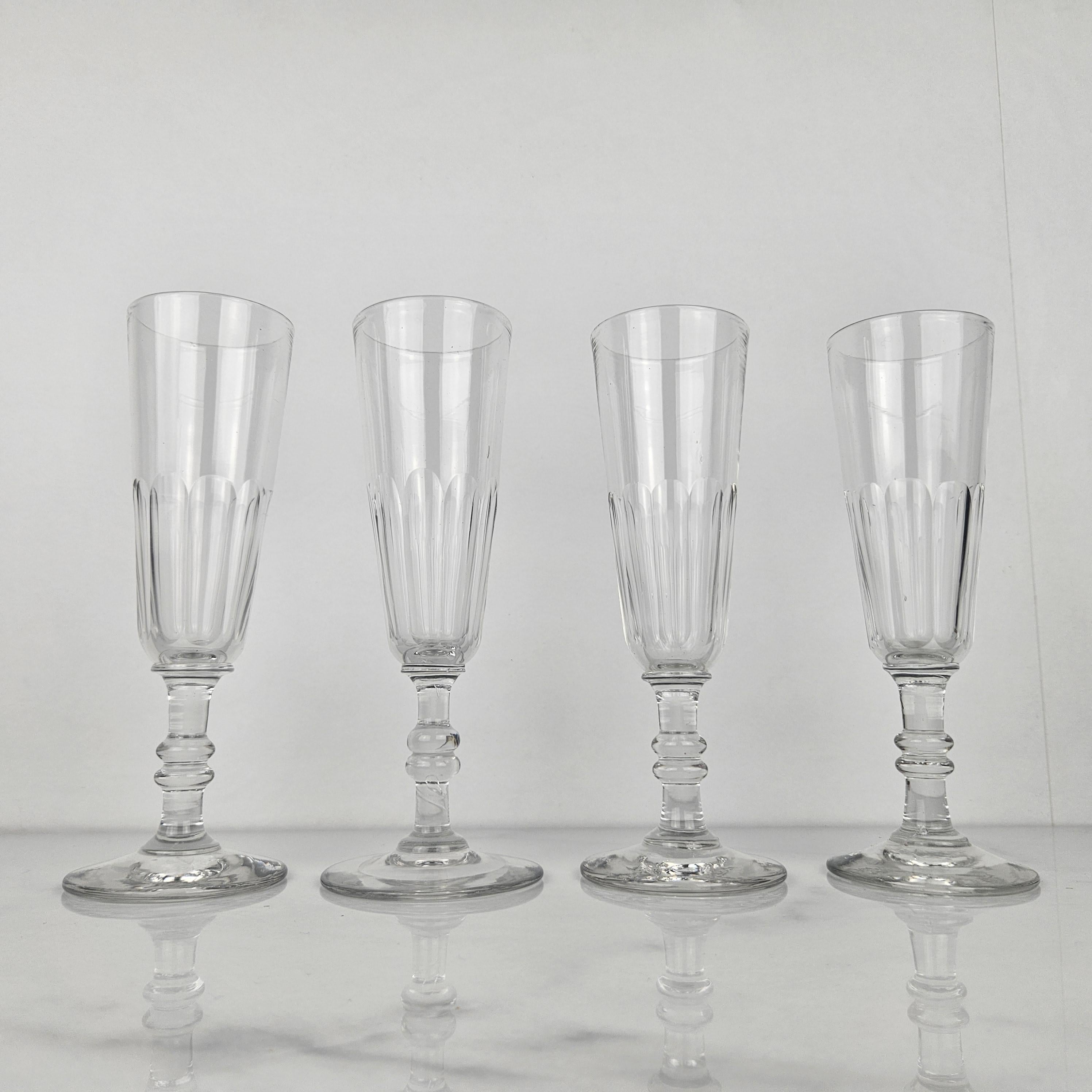 Un bel ensemble de quatre flûtes à champagne françaises en verre, fabriquées à la main vers 1870.  

Ces verres anciens sont soufflés à la bouche et taillés à facettes. 

Remarquez les très beaux détails et le design élégant.
Méticuleusement