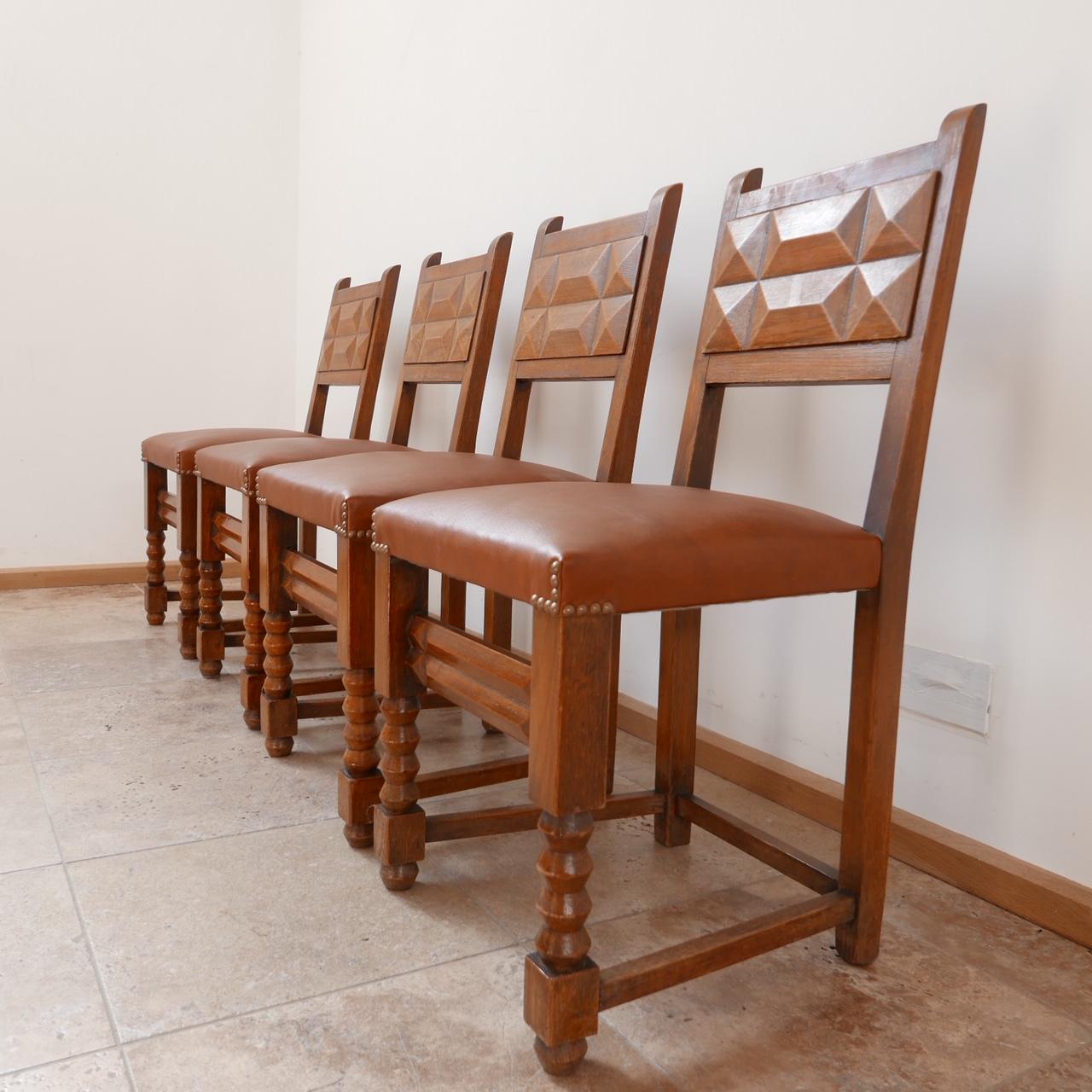 A set of four stylish dining chairs in the manner of Charles Dudouyt. 

French, c1940s. 

Stained wood and tan leather upholstery. 

Lots of decorative styling details from the back rests to the turned legs. 

Dimensions: 44 W x 49 D x 48