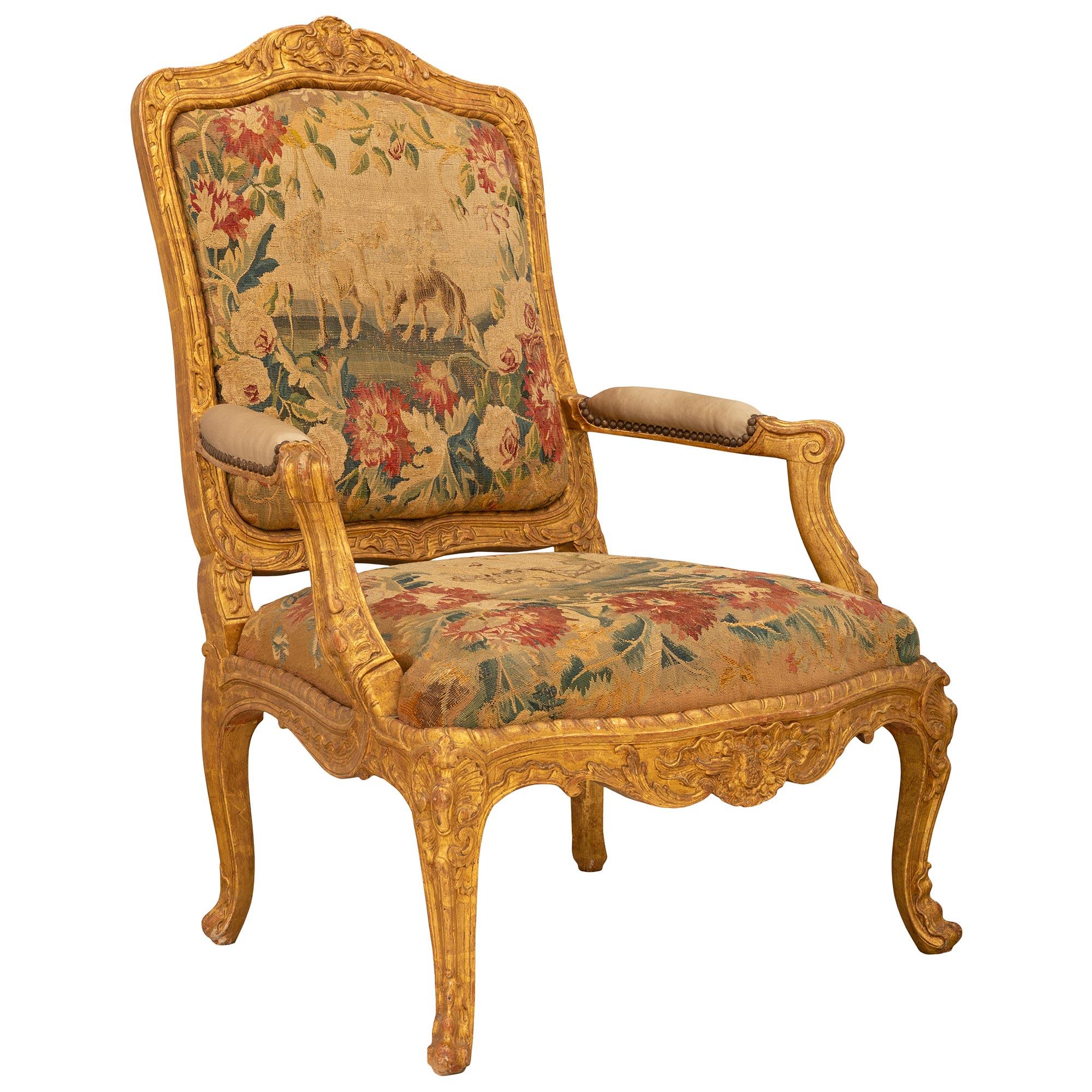 A beautiful and high quality set of four French early 19th century Louis XV st. giltwood and tapestry armchairs. Each armchair is raised by elegant cabriole legs with lovely carved foliate designs and finely carved seashell reserves at each corner.