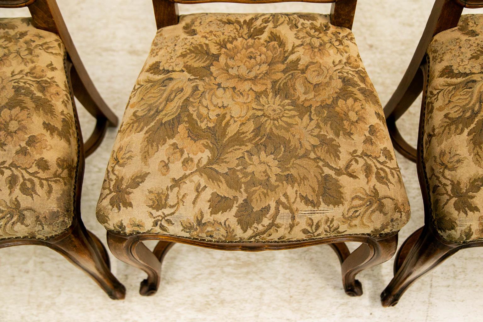 The crest rails of these chairs are carved with shaped scrolls. The back splats and styles are carved with incised beads framing a concave shape. The cabriole legs are connected by a shaped 
