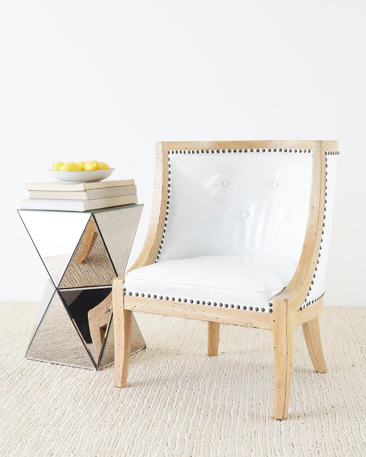 Stunning set of four French barrel back lounge or club chairs made in the Hollywood Regency period featuring a barrel or tub form. Wooden frame with an iconic Mid-Century Modern profile. Upholstered with a faux-patent leather tufted Naugahyde fabric