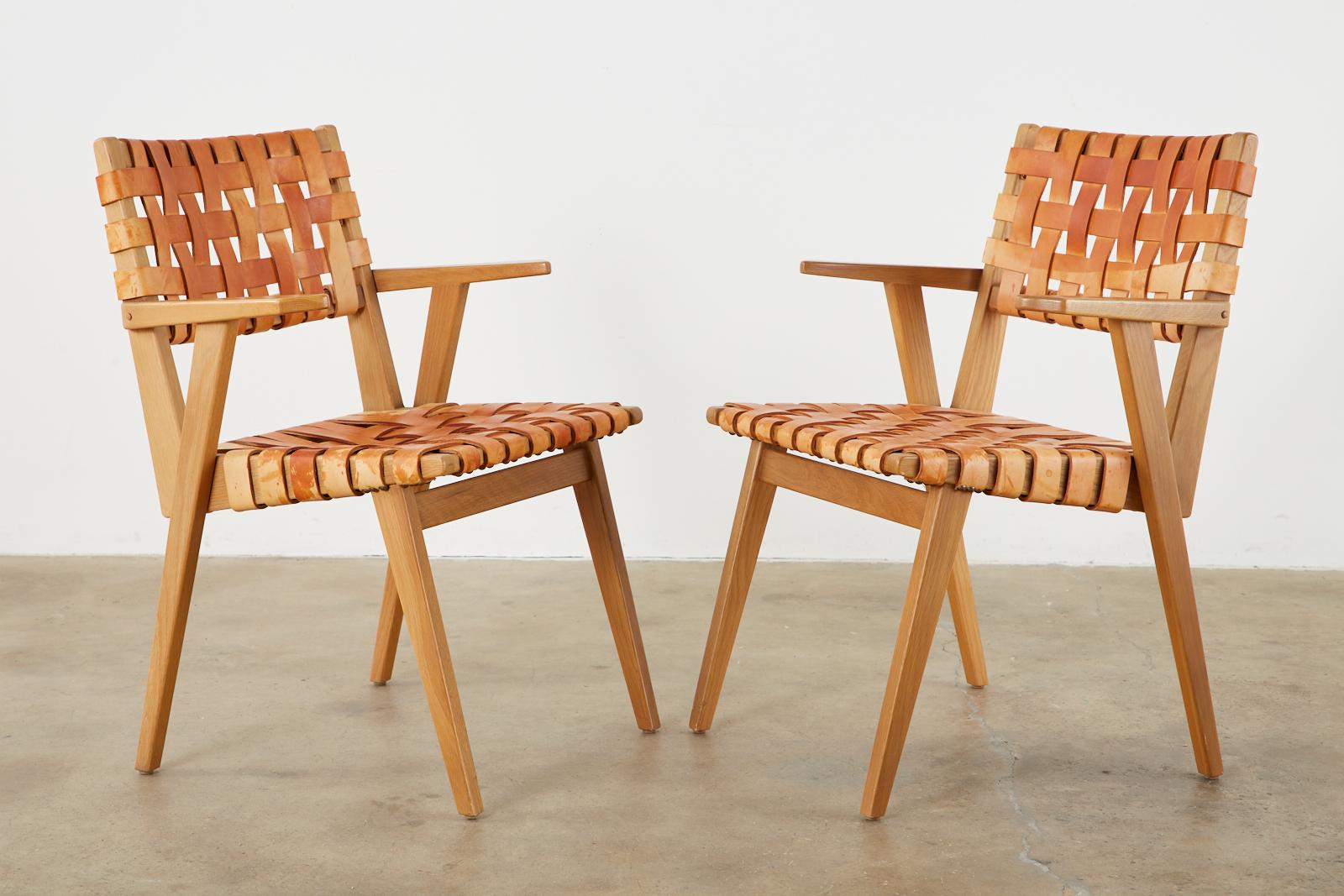 Fantastic set of four rare Mid-century modern style dining armchairs featuring thick woven, or webbed leather strap back and seats in the style and manner of Jens Risom for Knoll. The wide straps are affixed to the frames with brass tack nail studs.