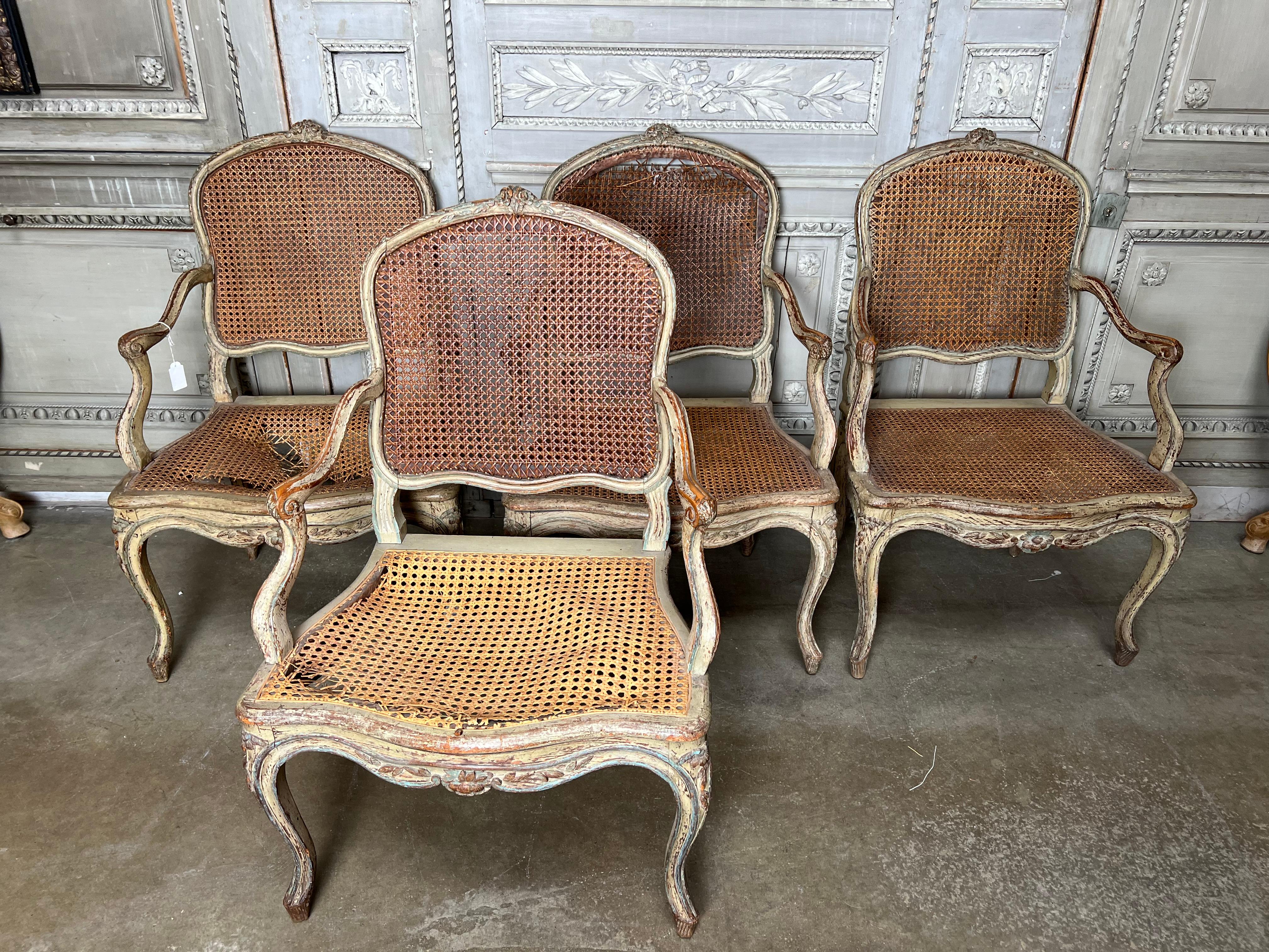 A set of four 18th century French Louis XV caned armchairs - fauteuils with an original grey painted finish with blue green accents.  This iconic suite of armchairs were in the dining room of the late philanthropist Brooke Astors Park Avenue