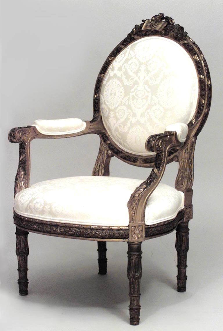 Set of 4 French Louis XVI style gilt carved arm chairs with carved oval back frame and white damask upholstery (19th Cent.).
