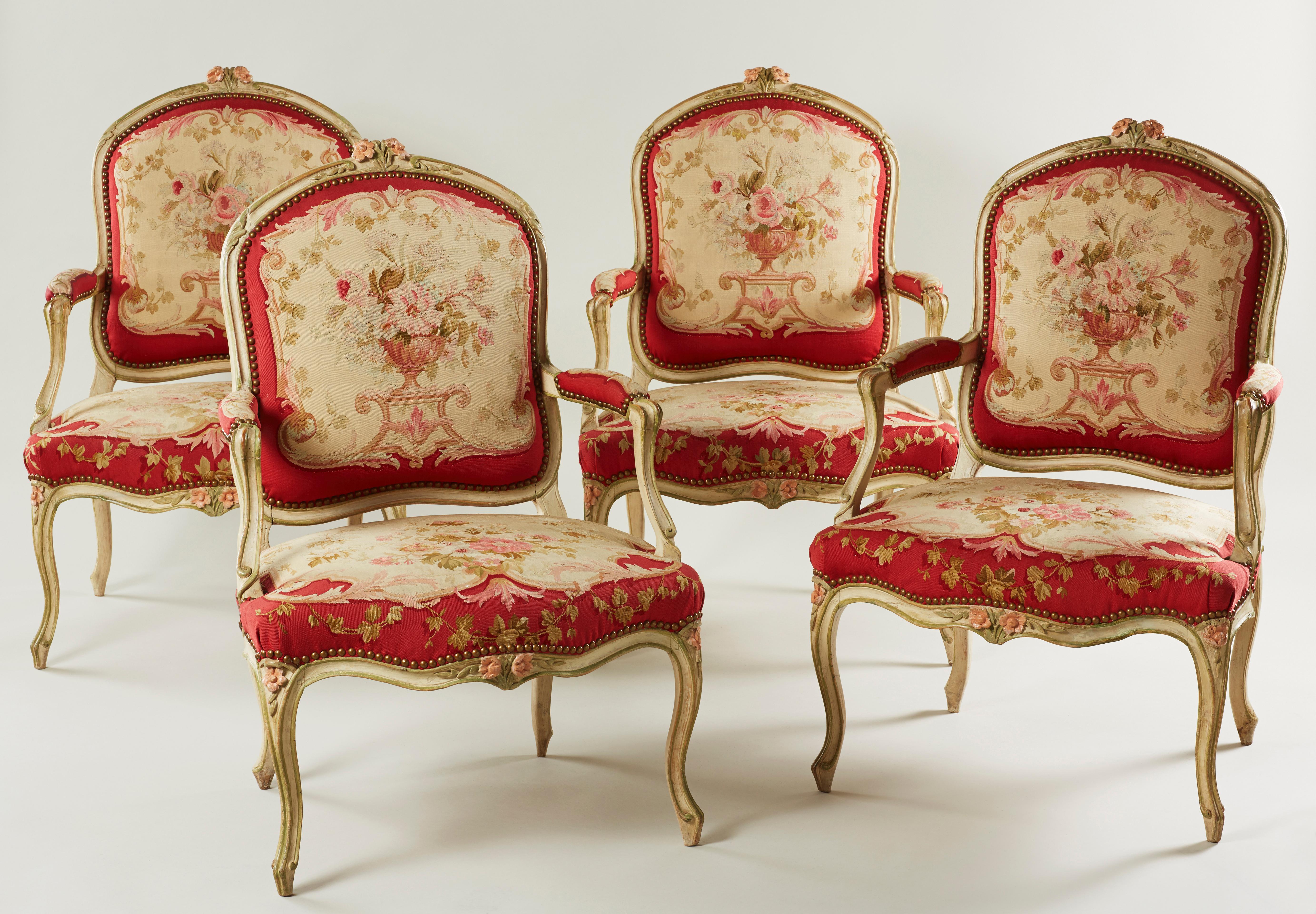 A rare and attractive set of four period Louis XV pale green and rose painted armchairs. Each with a flowerhead and foliate carved toprail, padded and scrolled arms and a serpentine seat, upholstered in brass studded 19th century Aubusson style