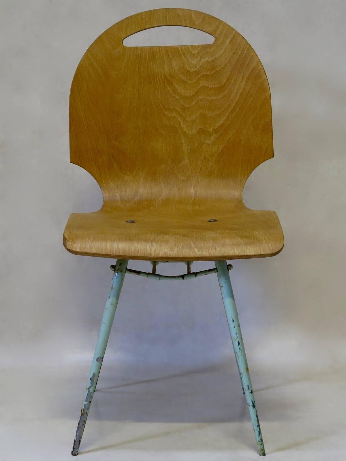 Four molded plywood chairs with unusual cut-out designs on the sides and top of the seats (forming a handle). The top is fixed to a tubular metal base, painted a light blue/green color, with tapering and splayed legs.

Very light and sturdy.