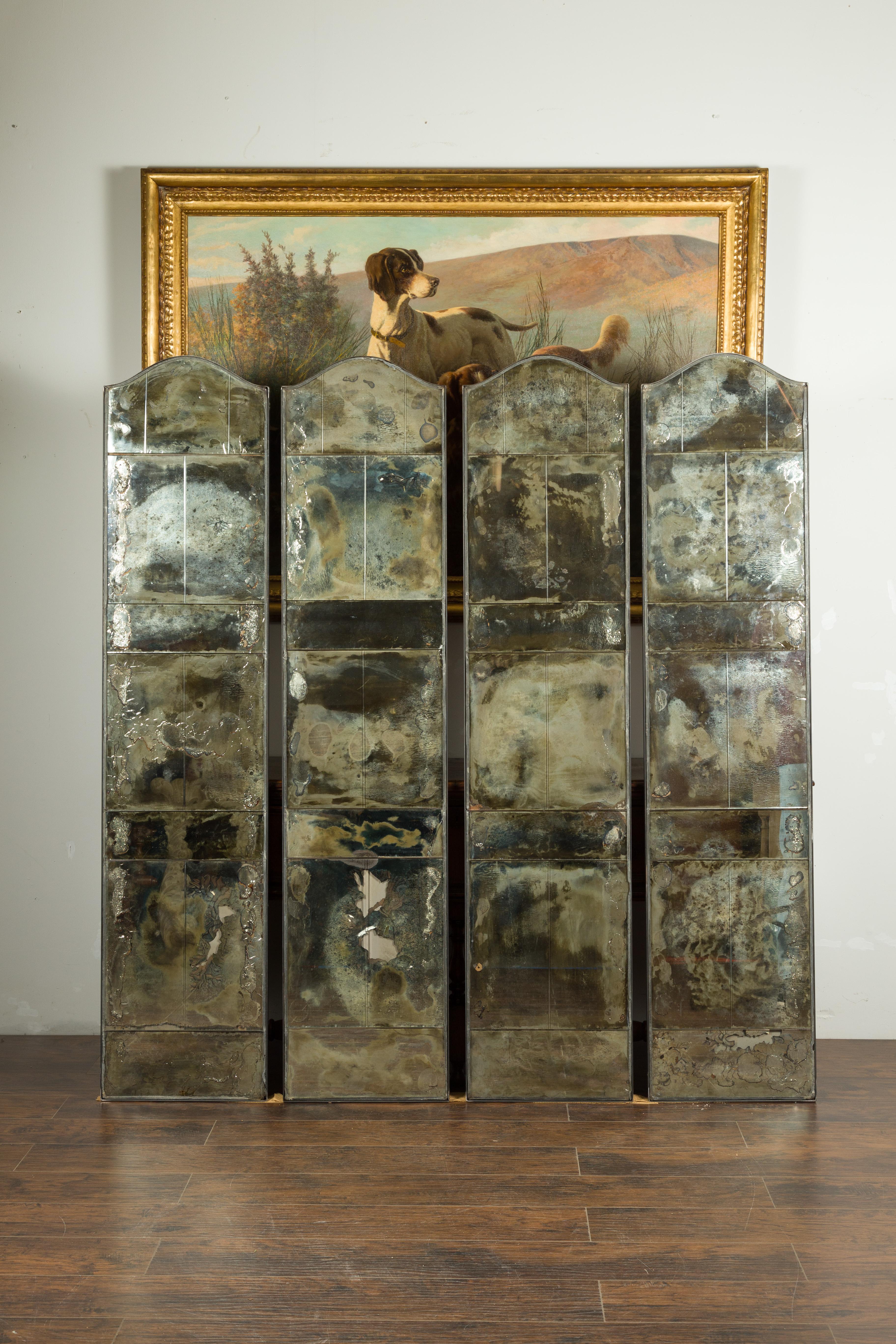 A set of four vintage French mirrored screens from the mid 20th century, with distressed appearances. Created in France during the midcentury period, this set of four mirrored screens draws our attention with its great presence and nicely weathered
