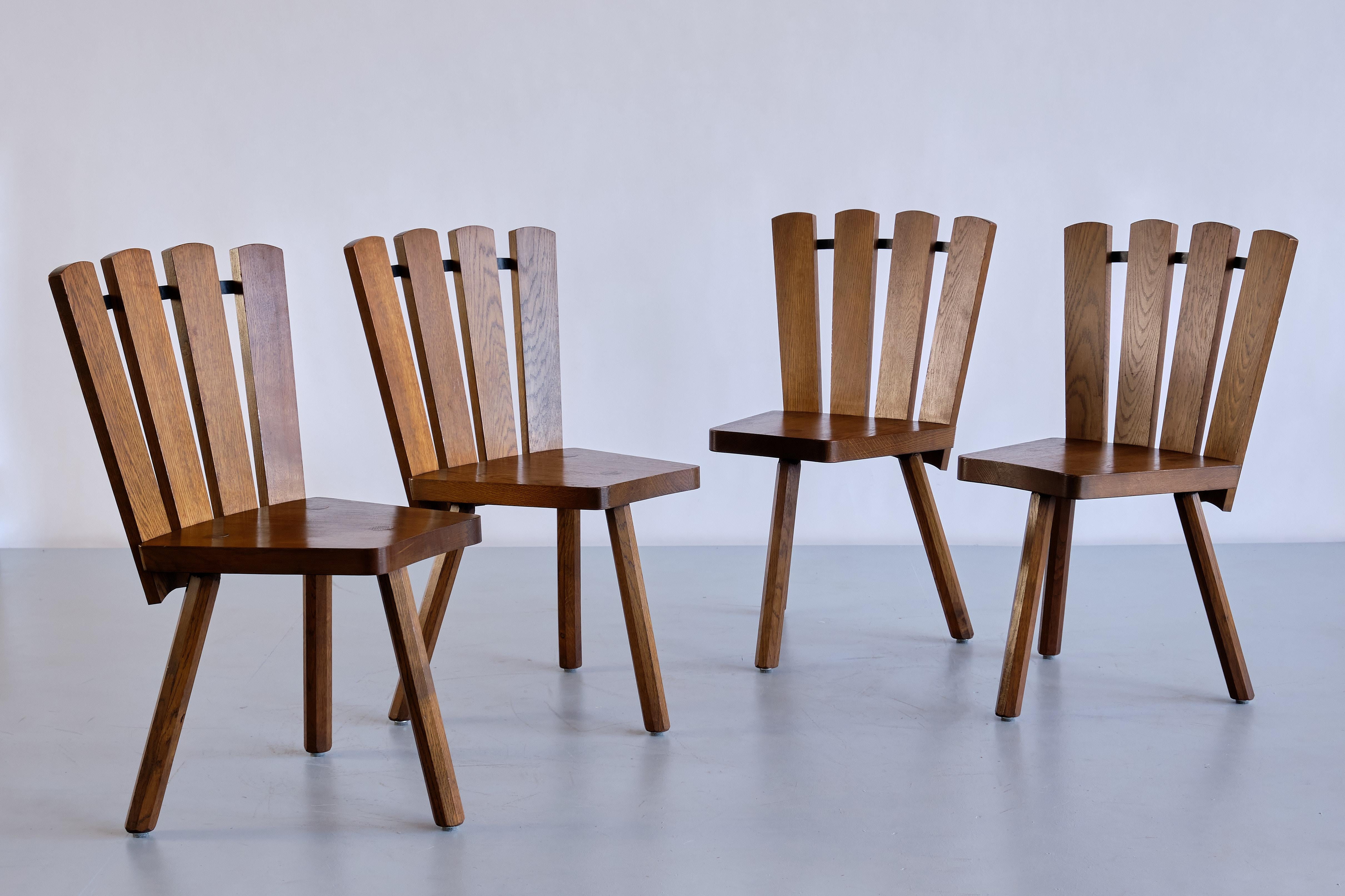 This striking set of four dining or side chairs was produced in France in the late 1950s. These sculptural chairs were handcrafted and are made of stained solid oak wood. The distinct design is marked by the fan shaped back, consisting of four slats