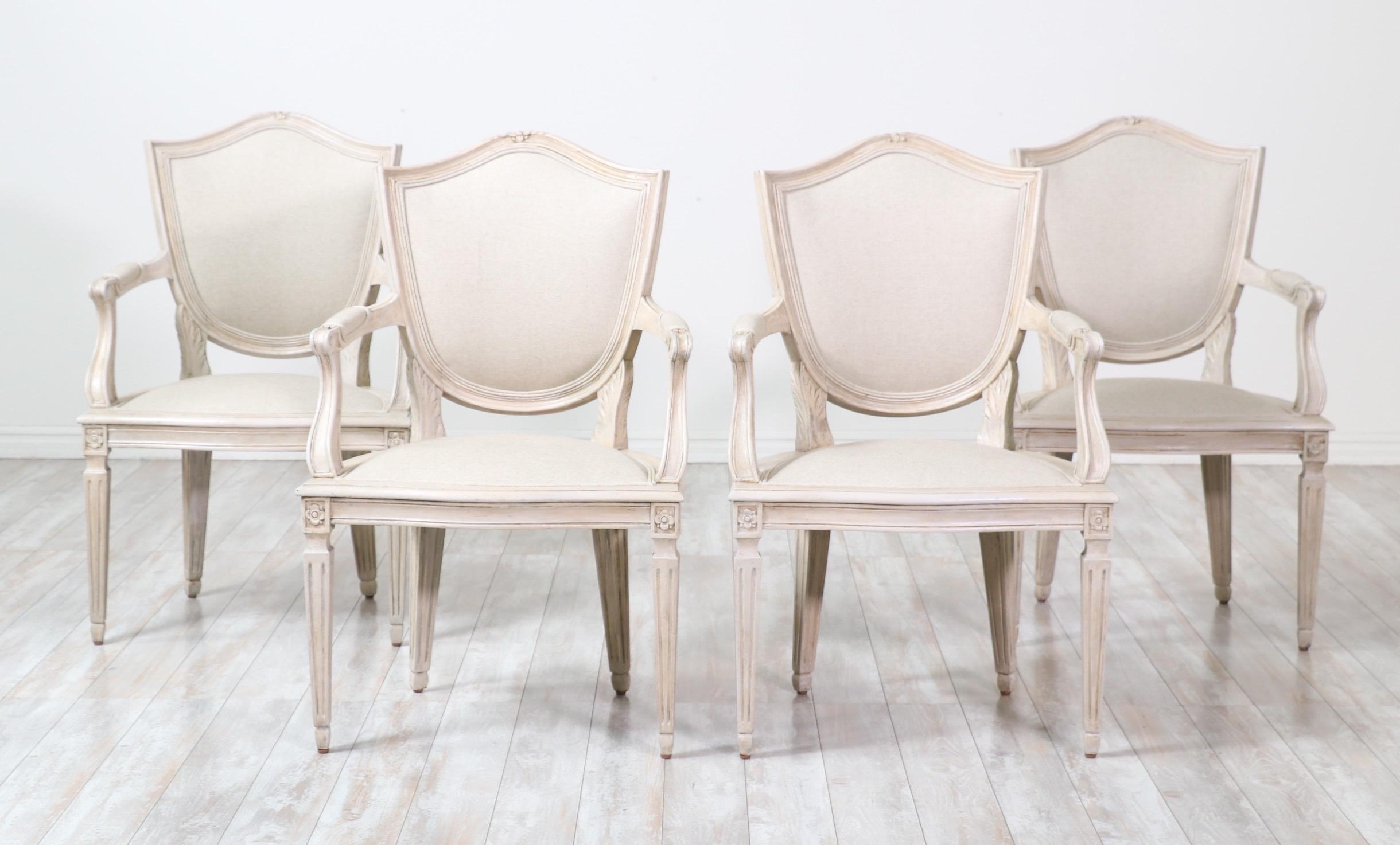 Beautiful, 1940s French set of four painted armchair in the Neoclassical style.

Each chair consists of an elegantly carved wood frame with a distressed greige paint finish and has been newly upholstered in a cotton linen canvas textile. 

The