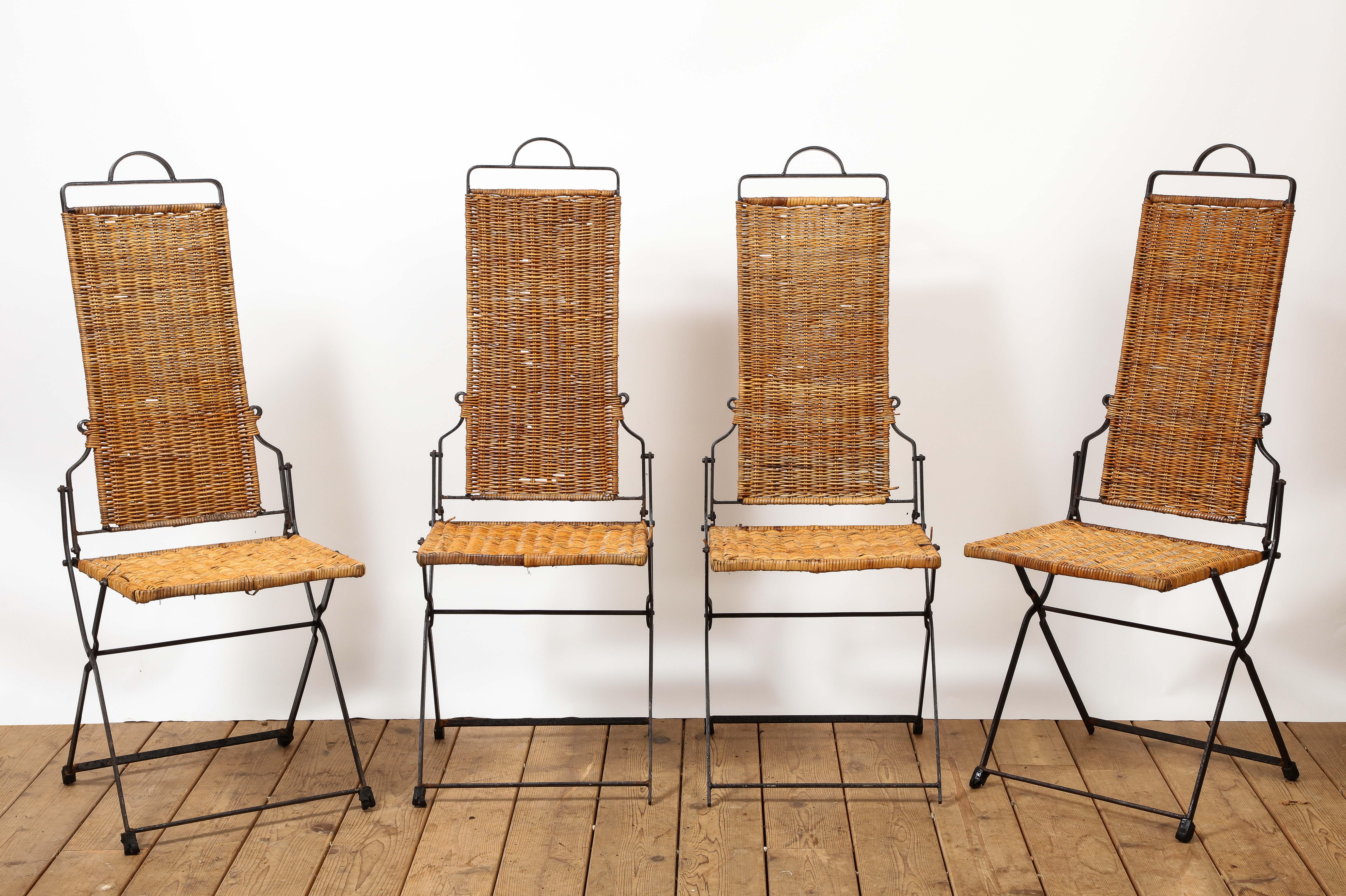 Set of four (4) 20th century French Provincial style wicker and iron folding chairs. Streamlined profile, rounded carrying handle at the top of the chair. Great for outdoor. 