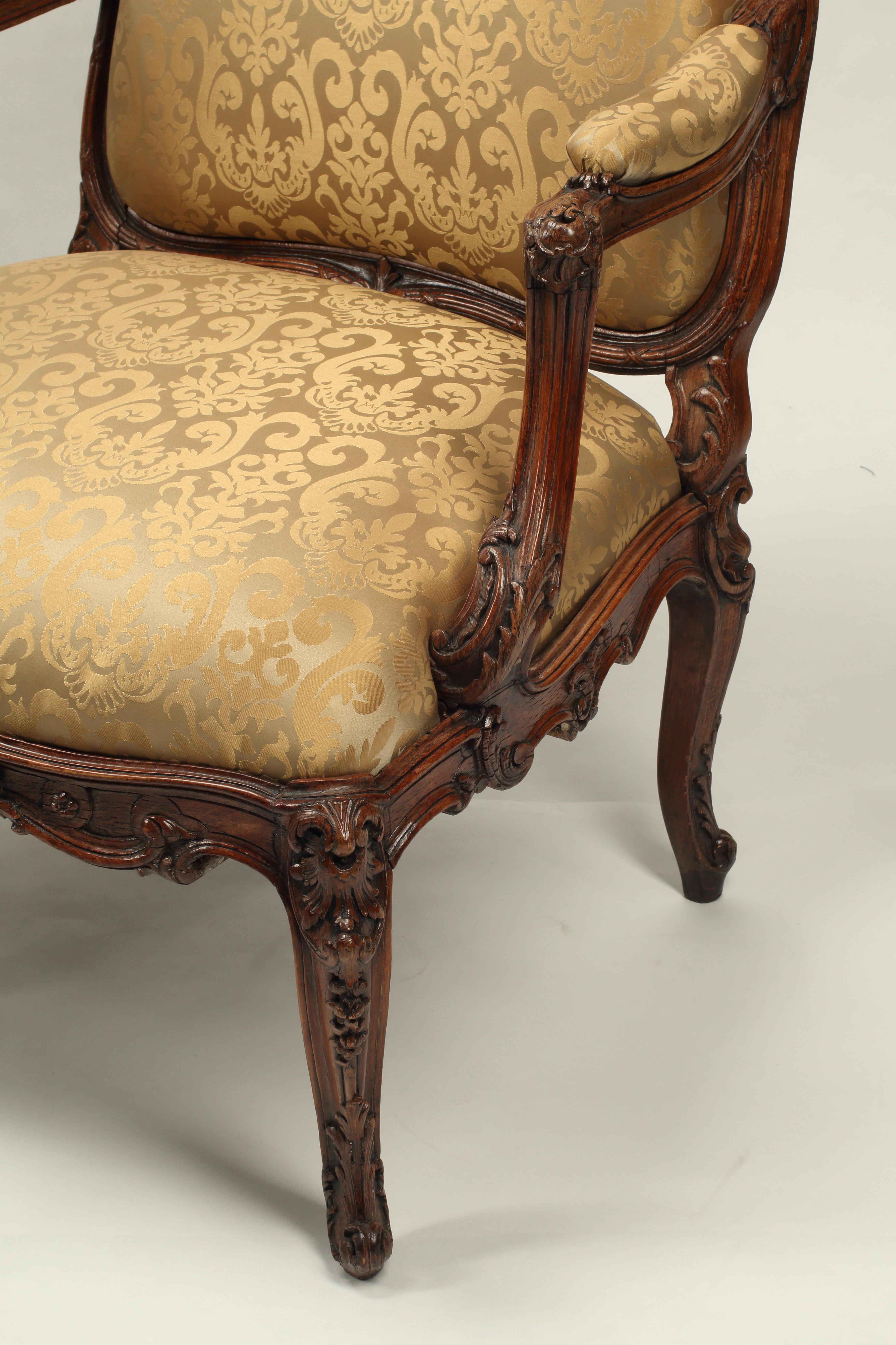 Questo set di quattro poltrone in noce è un esempio impressionante dello stile Régence francese. Intagliata a mano nel XIX secolo, i motivi a conchiglia e a fogliame tipici dell'epoca ornano la corona arcuata dello schienale e le spalle e si