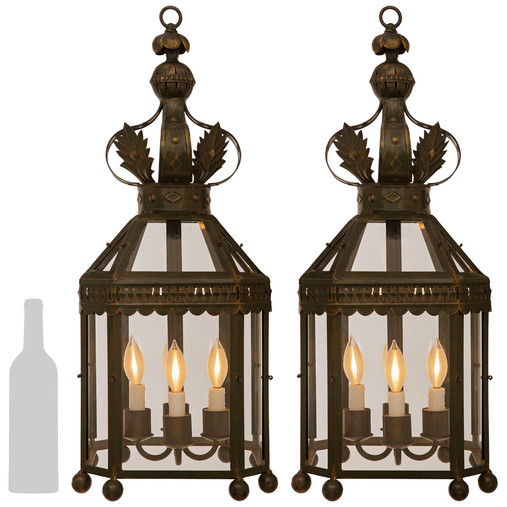 A handsome set of four French Turn of the Century Louis XVI st. Wrought Iron lanterns. Each octagonal four arm four light lantern consist of an eight sided cage with bottom spheres below each corner. Along the top edge is a scalloped Iron band below